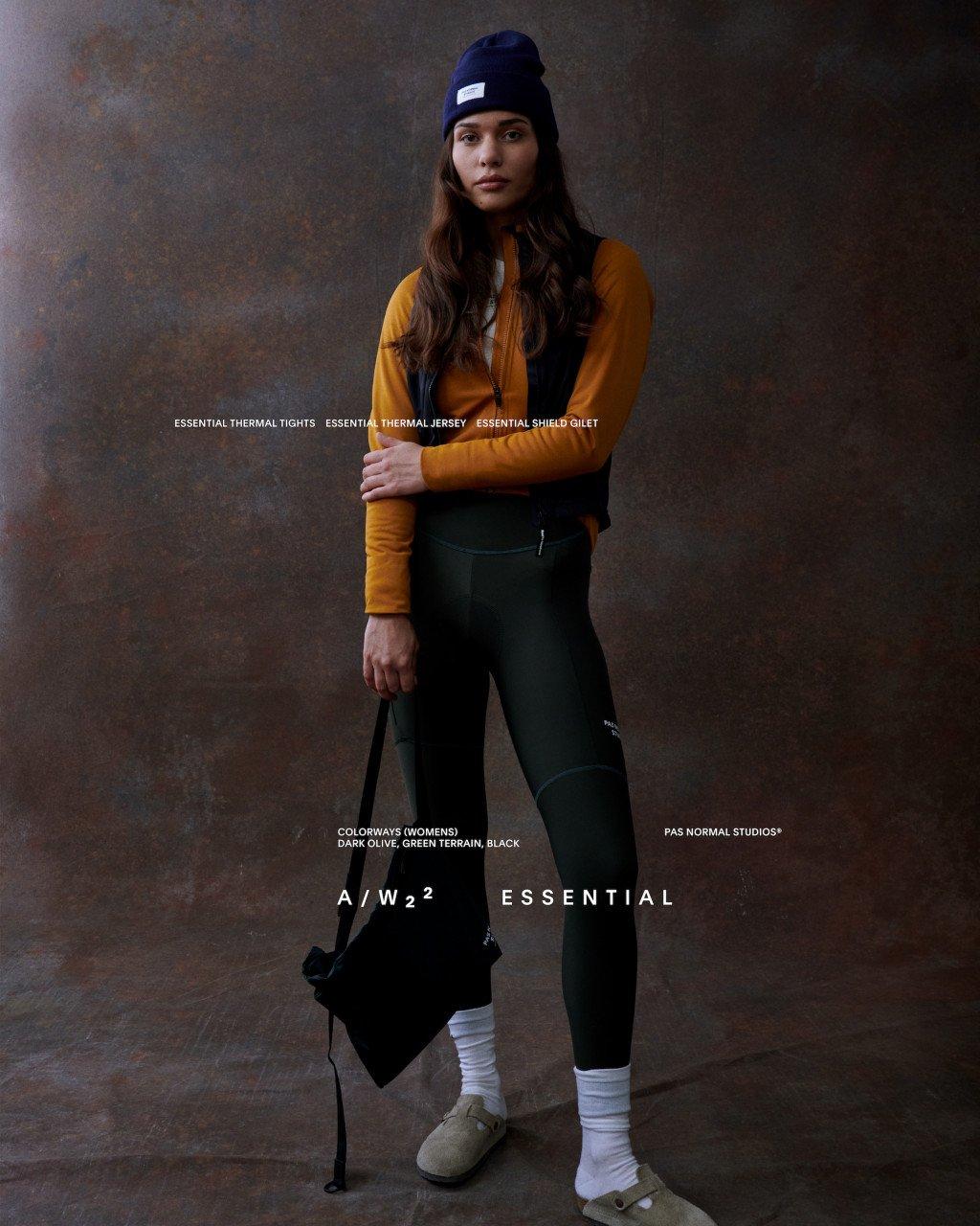 Model wearing Women's Essential collection yellow thermal jersey, dark green tights and navy beanie in studio