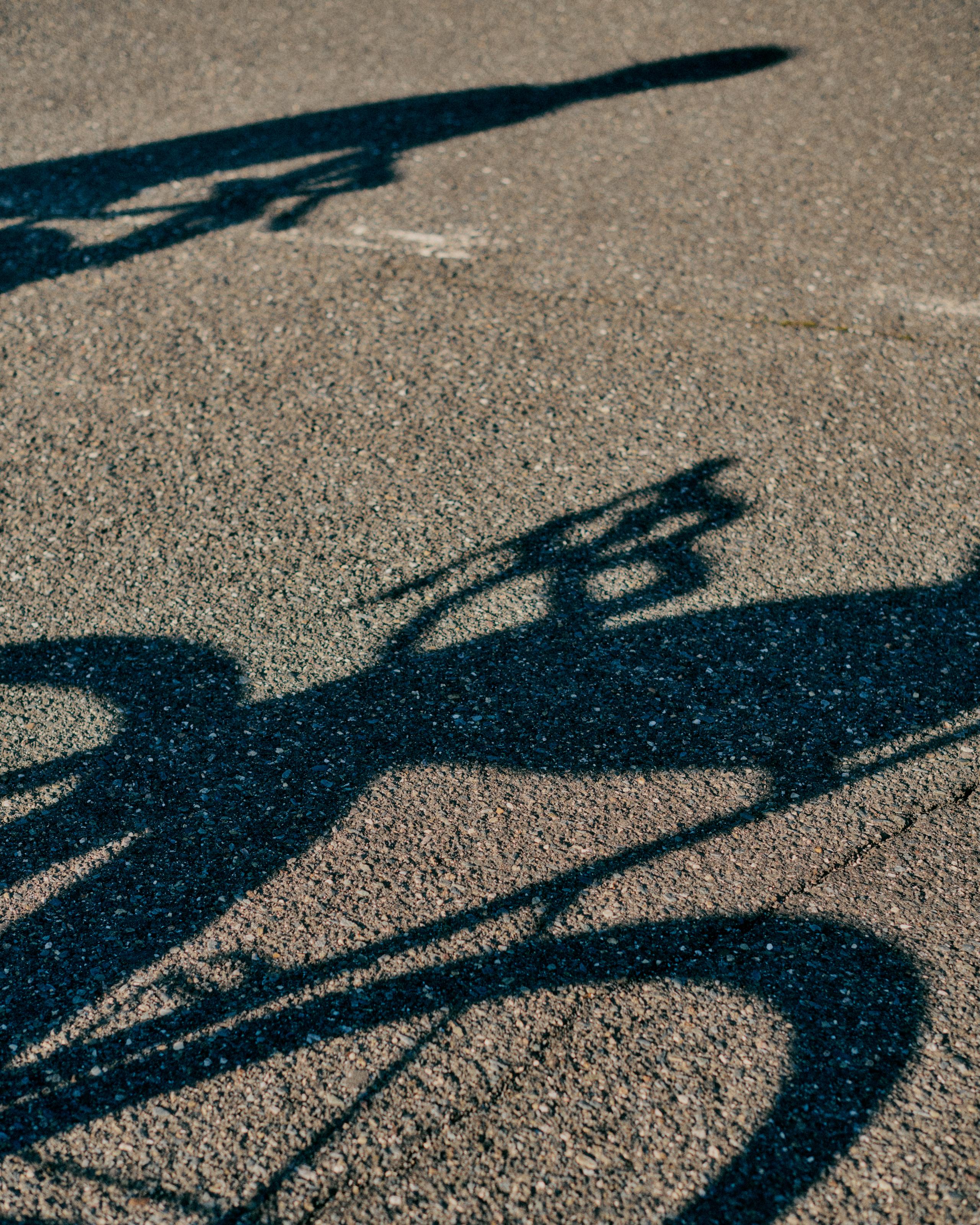 Shadows of cyclist and bicycle cast on asphalt road surface