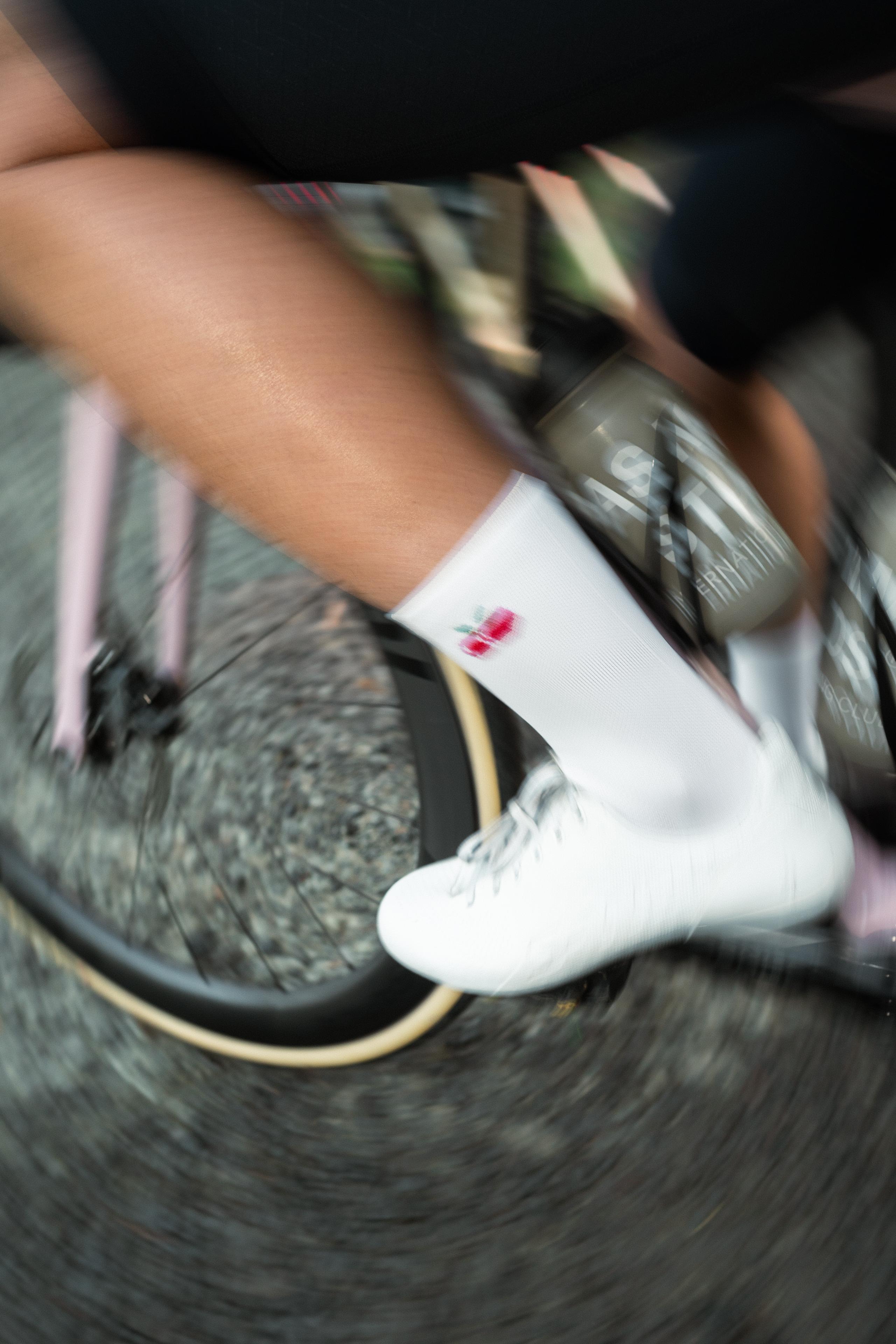 White cycling socks with logo detail worn while riding, motion blur effect