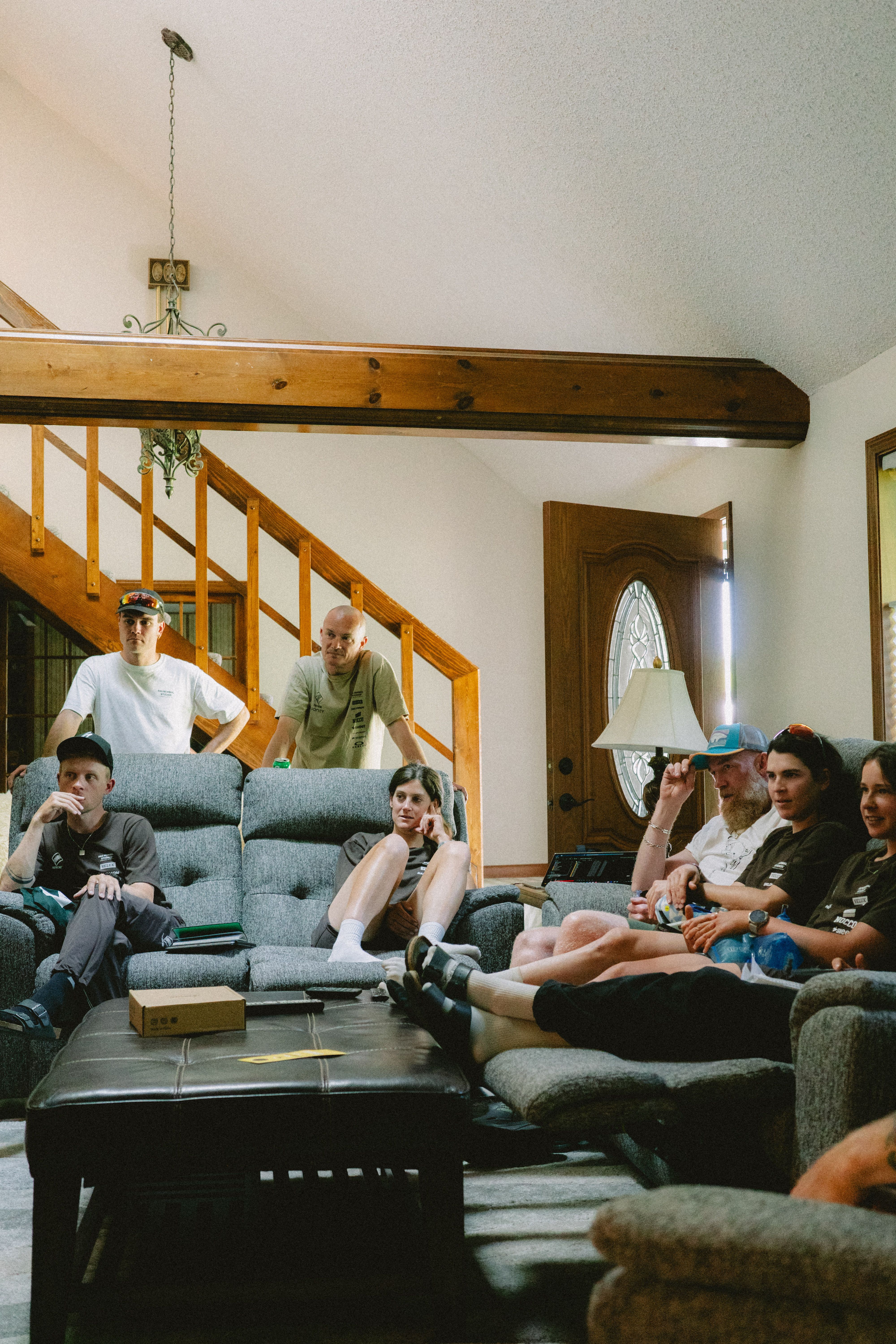 Cycling team relaxing in living room before Unbound Gravel race wearing casual cycling apparel