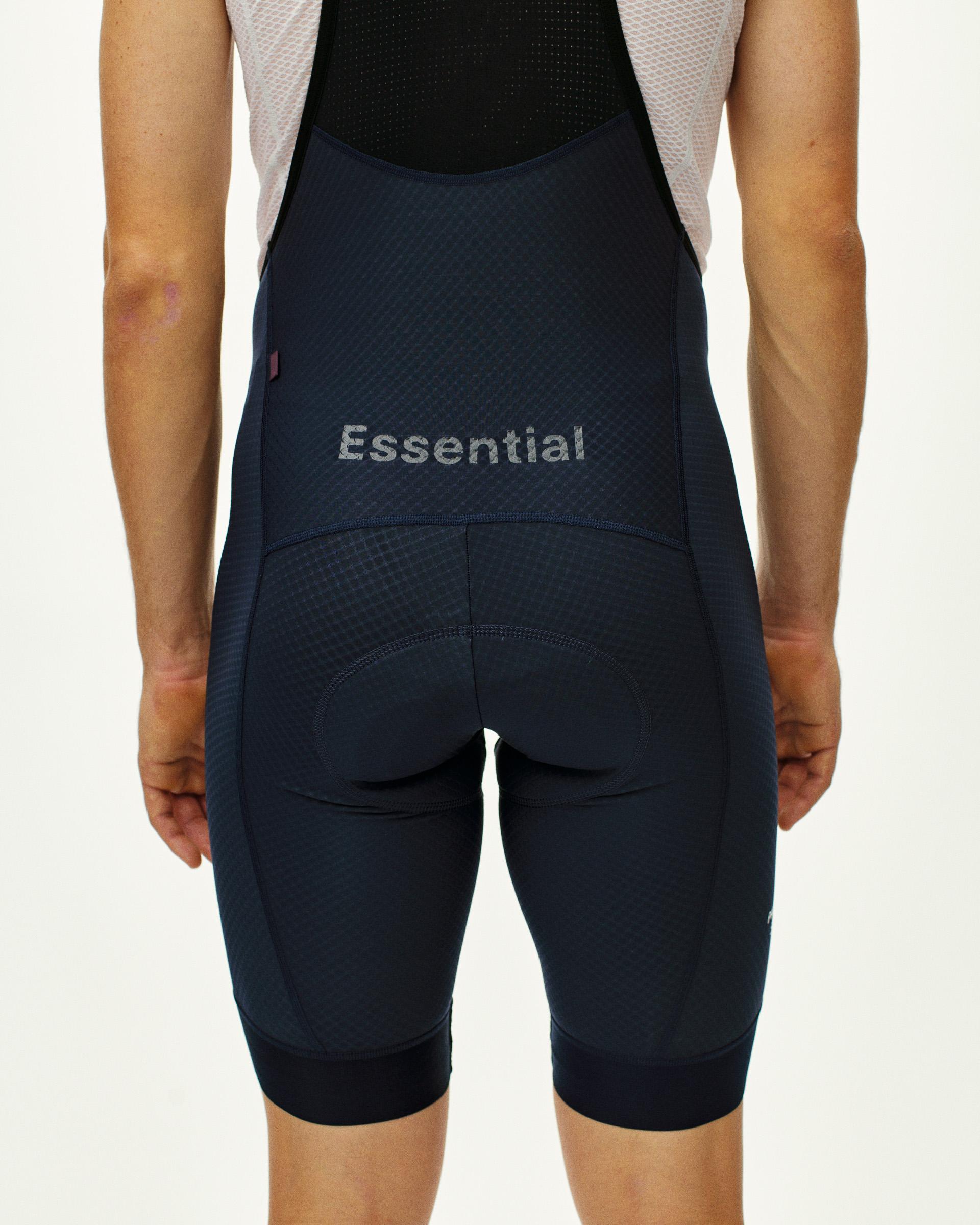 Navy Essential cycling bibs on model, rear view with Essential text on lower back