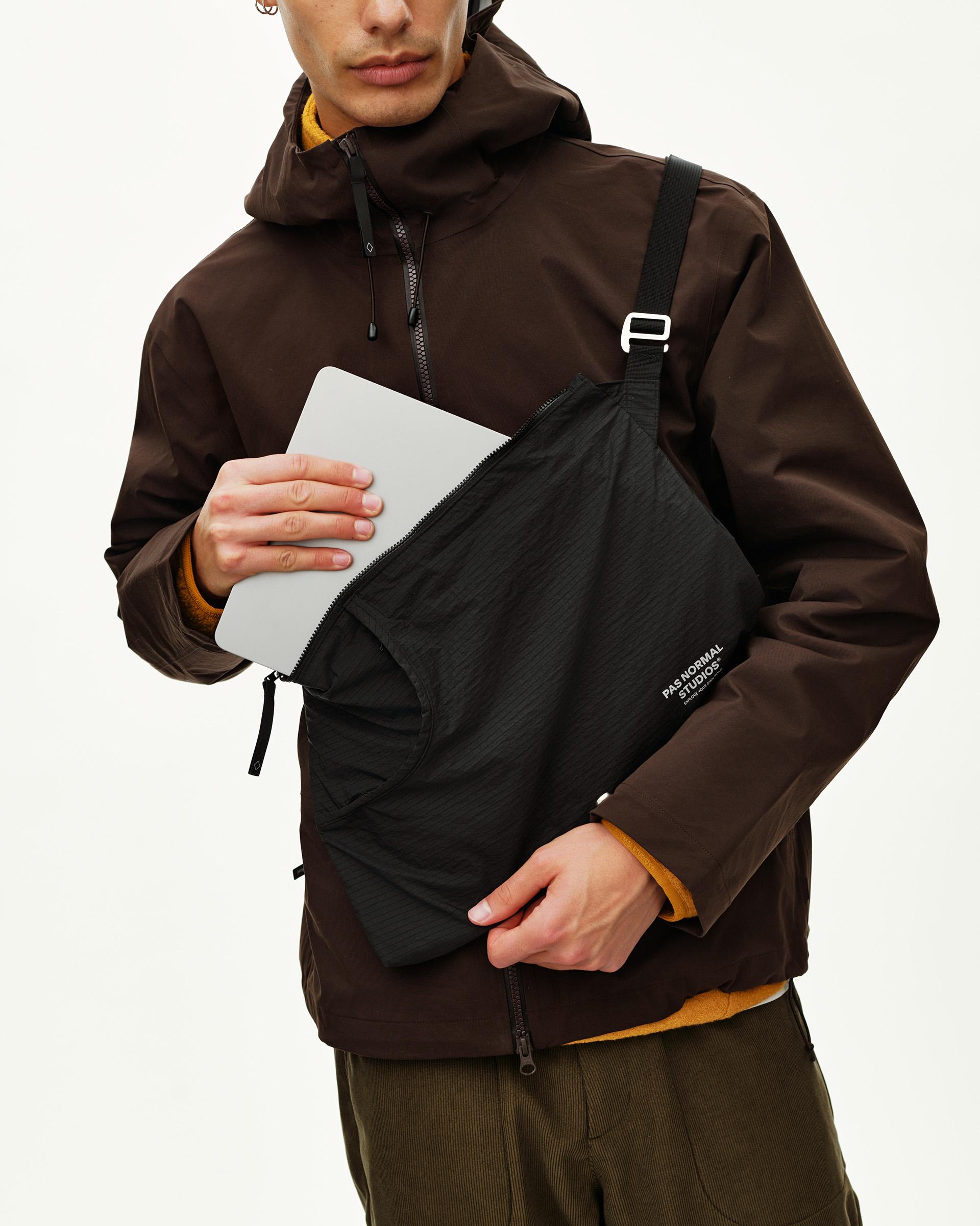 Black Off-Race Tech Musette 2.0 shoulder bag on model, opened showing laptop being removed