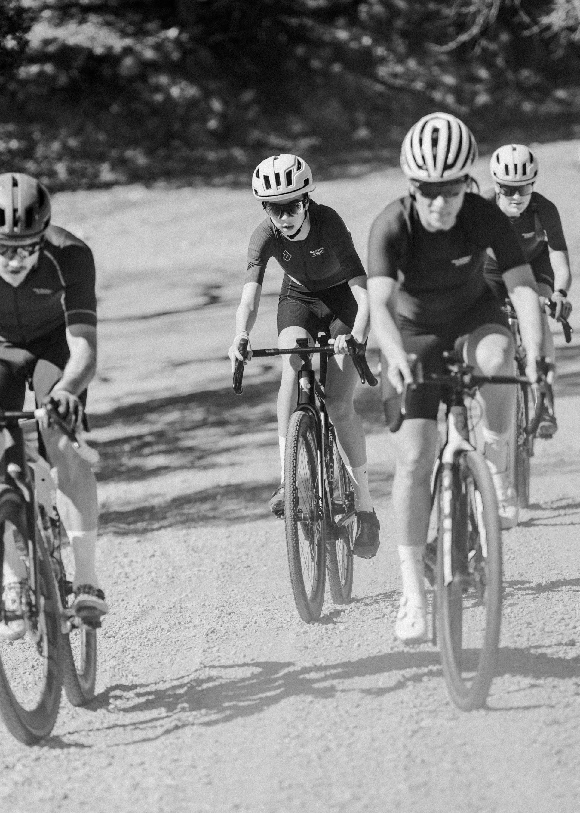 Cyclists in aerodynamic position racing on road in black and white