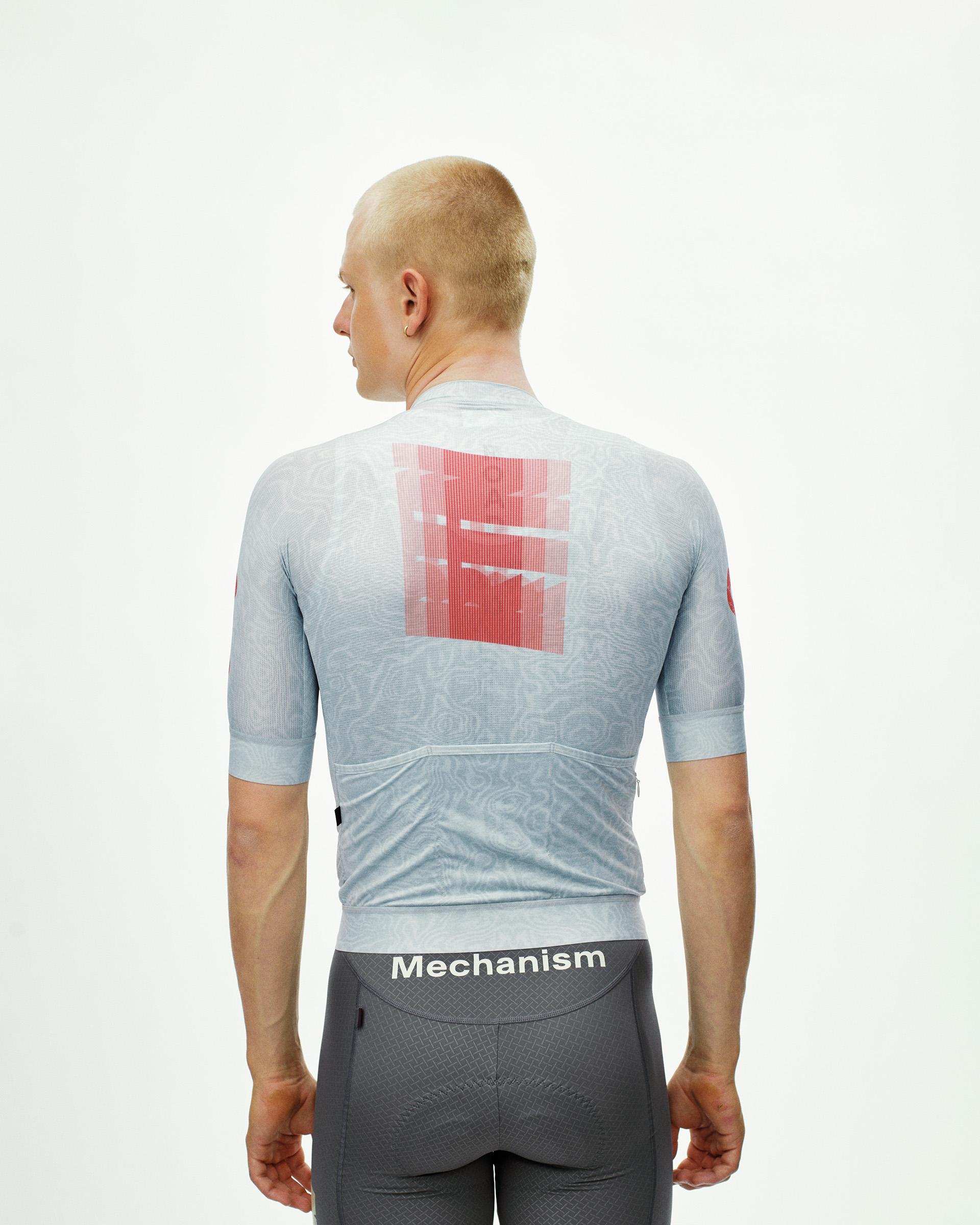 Light Aqua Mechanism cycling jersey on model, rear view with red graphic back print