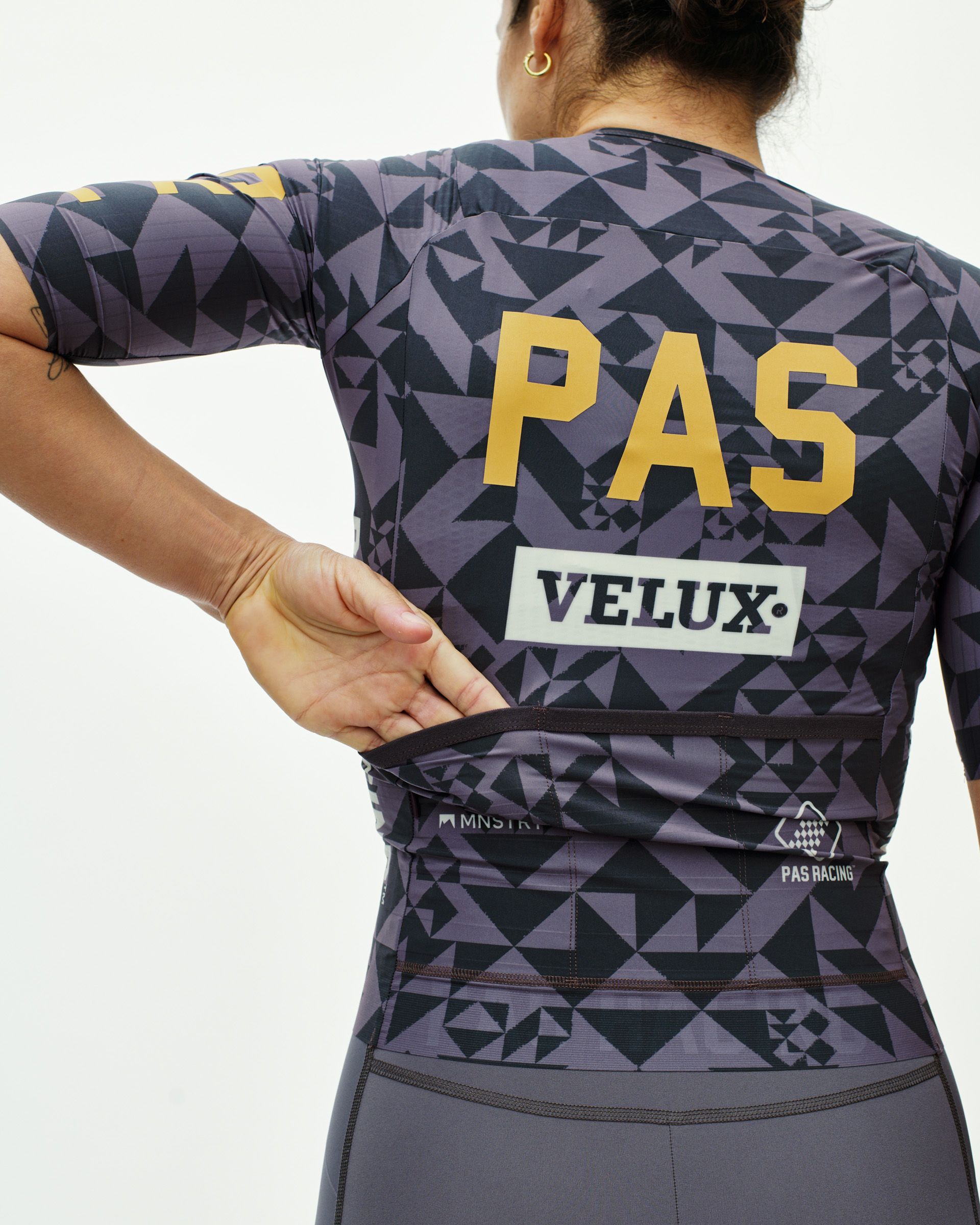 Origami Grey PAS Mechanism Pro women's cycling jersey, rear view on model with geometric print and gold PAS back graphic