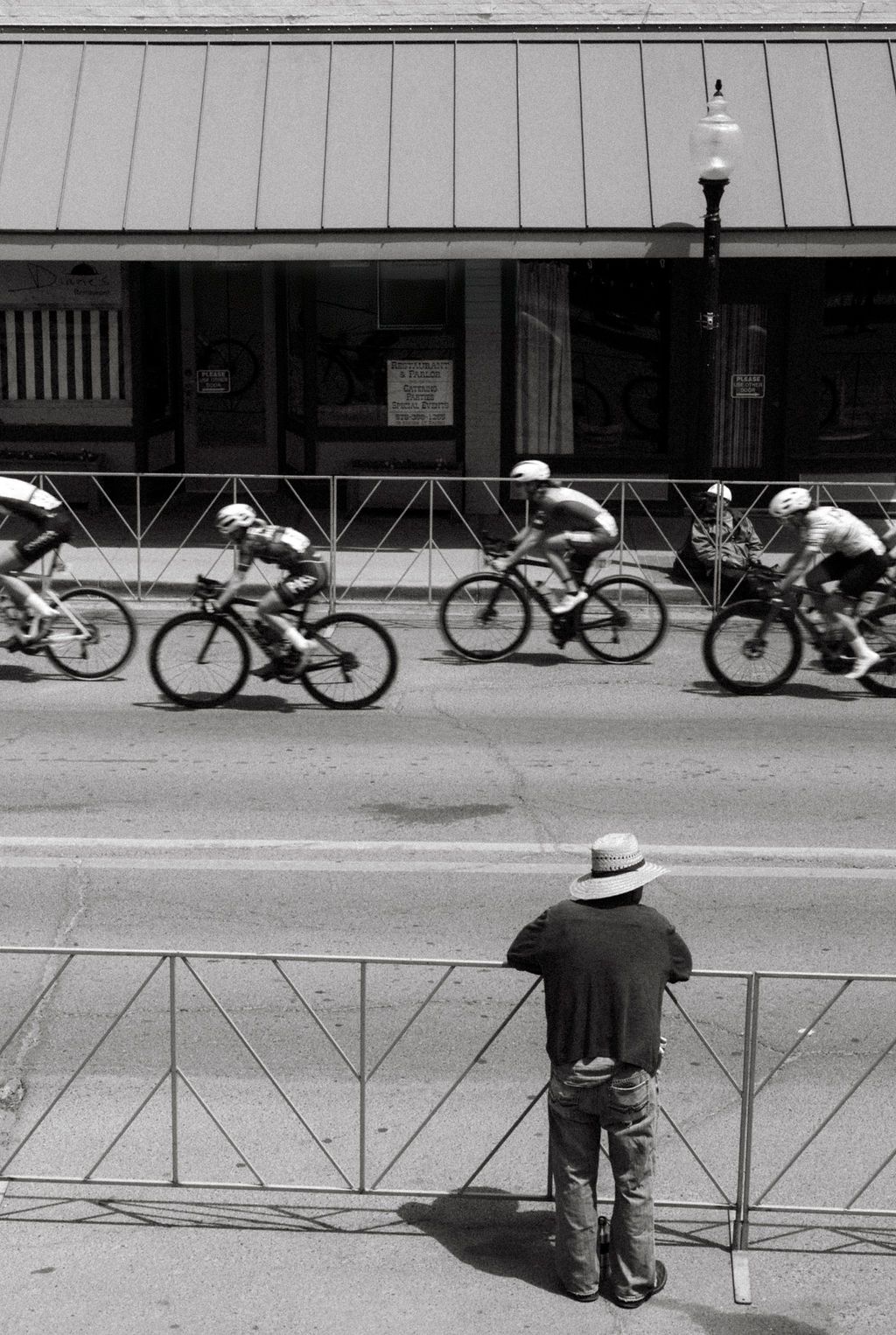 Cyclists racing past spectator during Tour of the Gila in black and white