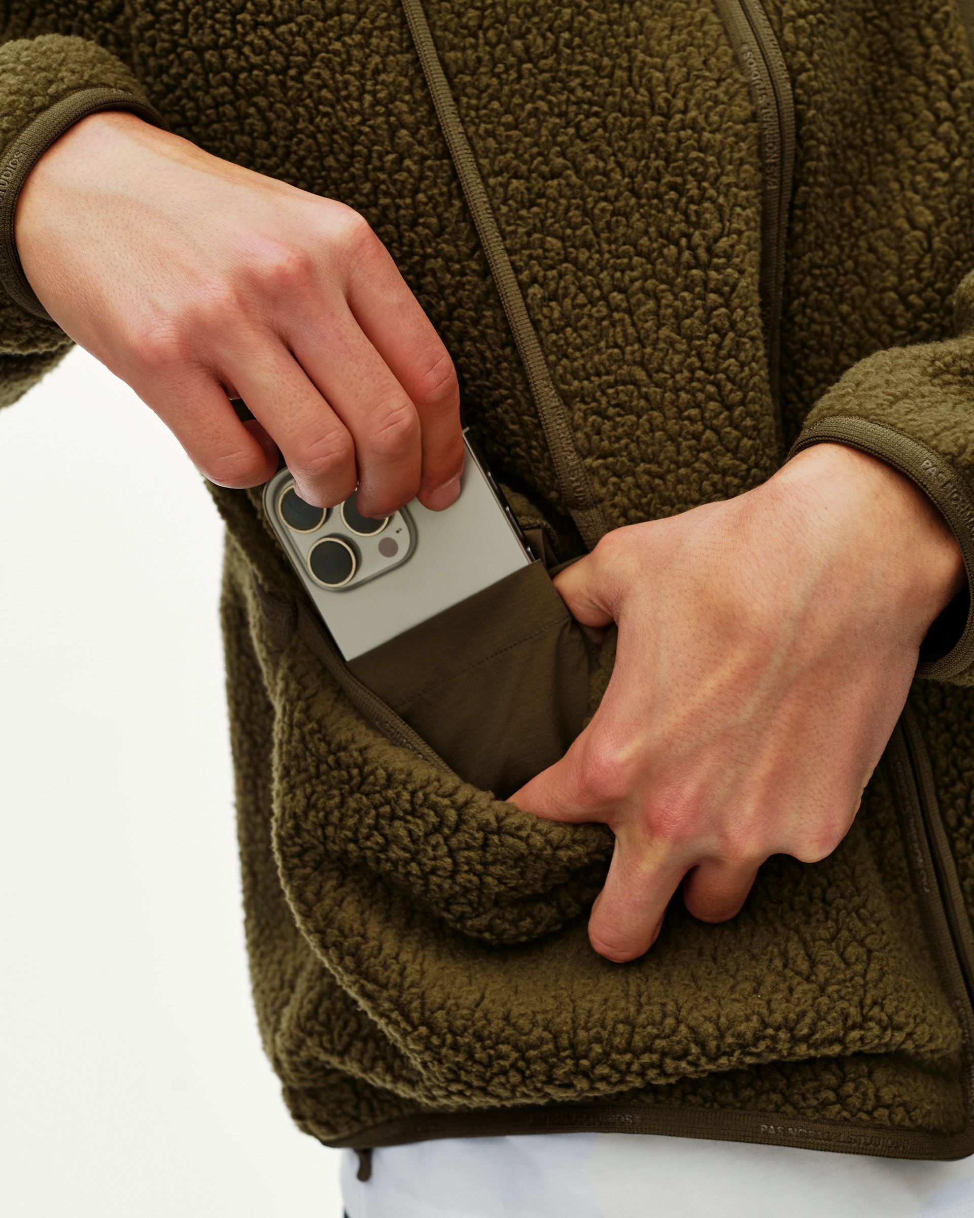 Deep Olive Off-Race Pile Fleece jacket detail on model showing zip pocket with phone being removed