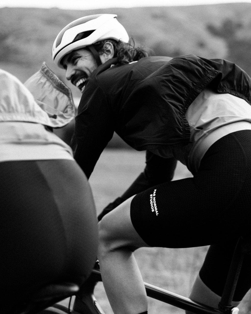 Cyclist in aero position wearing white helmet and dark cycling apparel with knee warmers