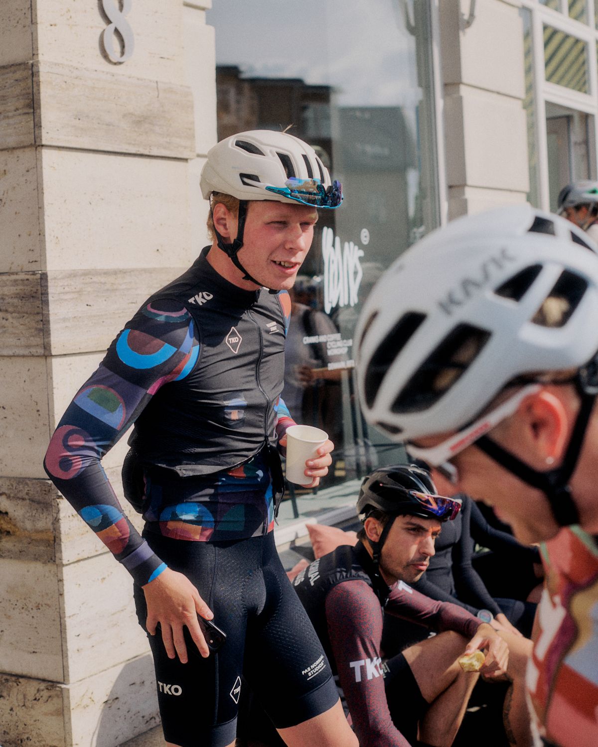Cyclist wearing colorful patterned jersey and shorts with white helmet at Brand Summit event