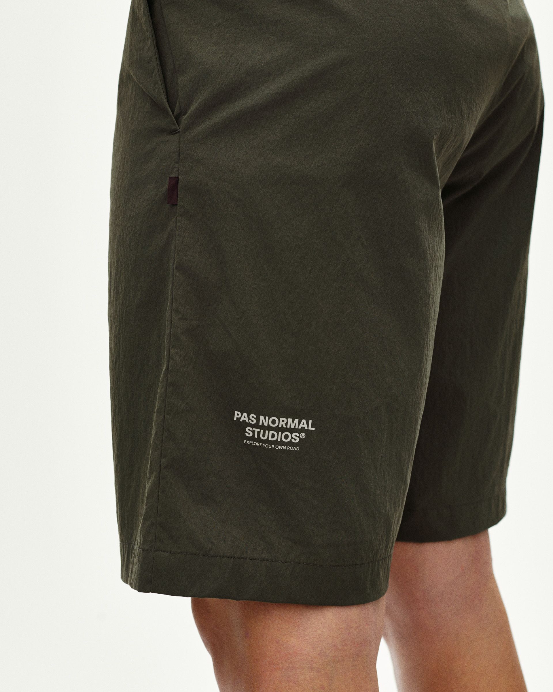Dark Grey Off-Race Light Tech shorts on model, side view with white leg logo