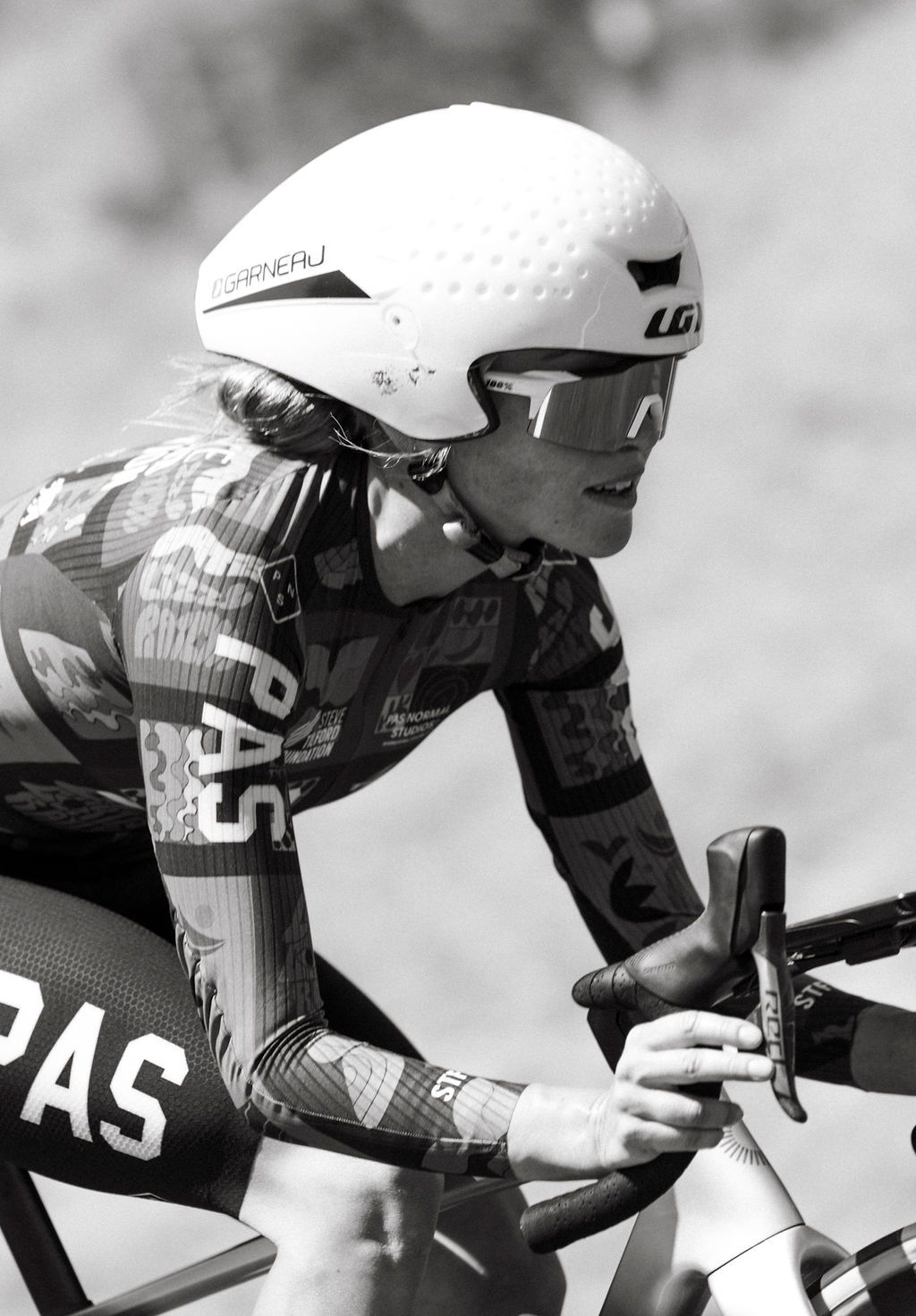 Cyclist in aerodynamic position wearing time trial helmet and skinsuit with geometric pattern during race