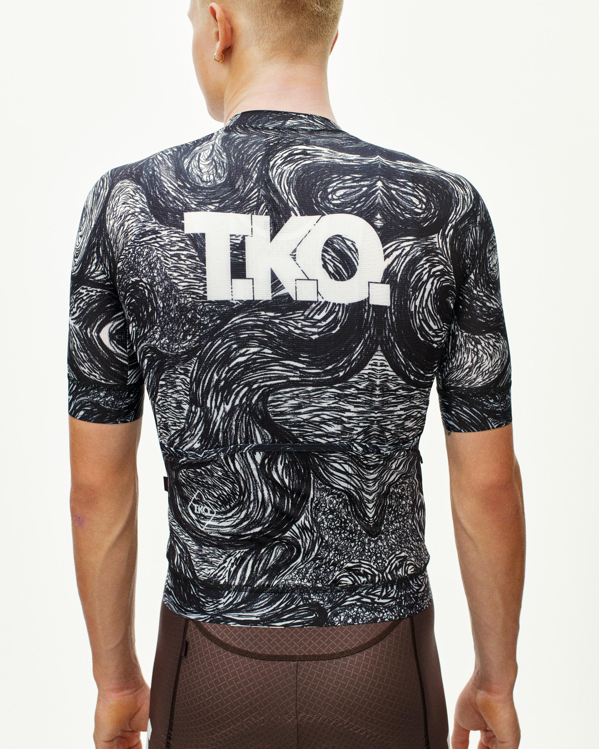 Iron Grey T.K.O. Mechanism cycling jersey on model, rear view with swirling black and white print and white T.K.O. back logo