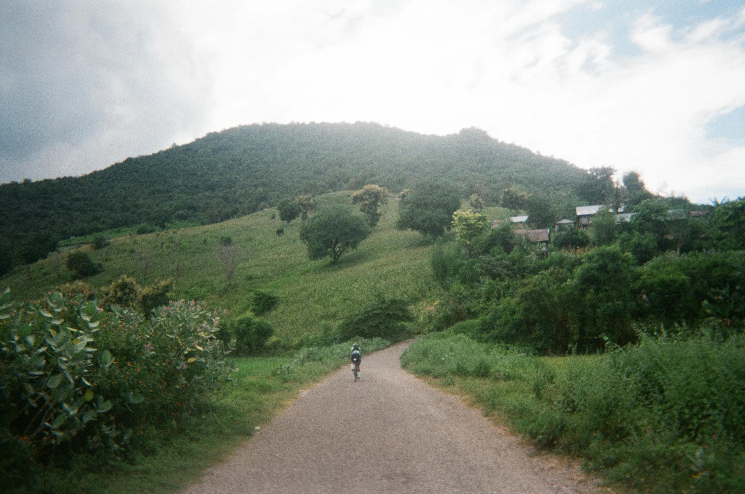 Cyclist on rural road through lush green hills and countryside in Indonesia
