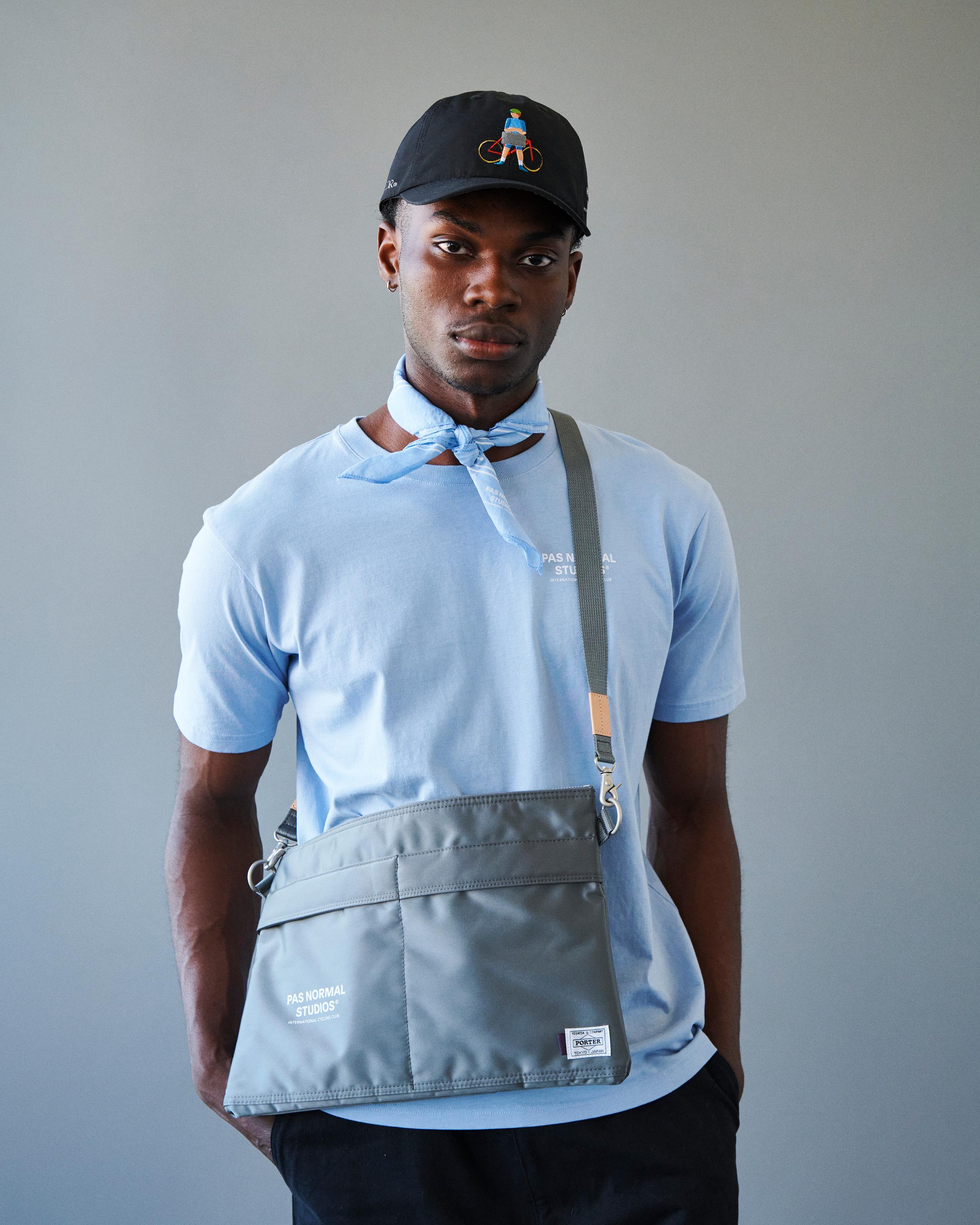 Grey Porter-Yoshida musette bag on model, front view with adjustable shoulder strap and logo patch