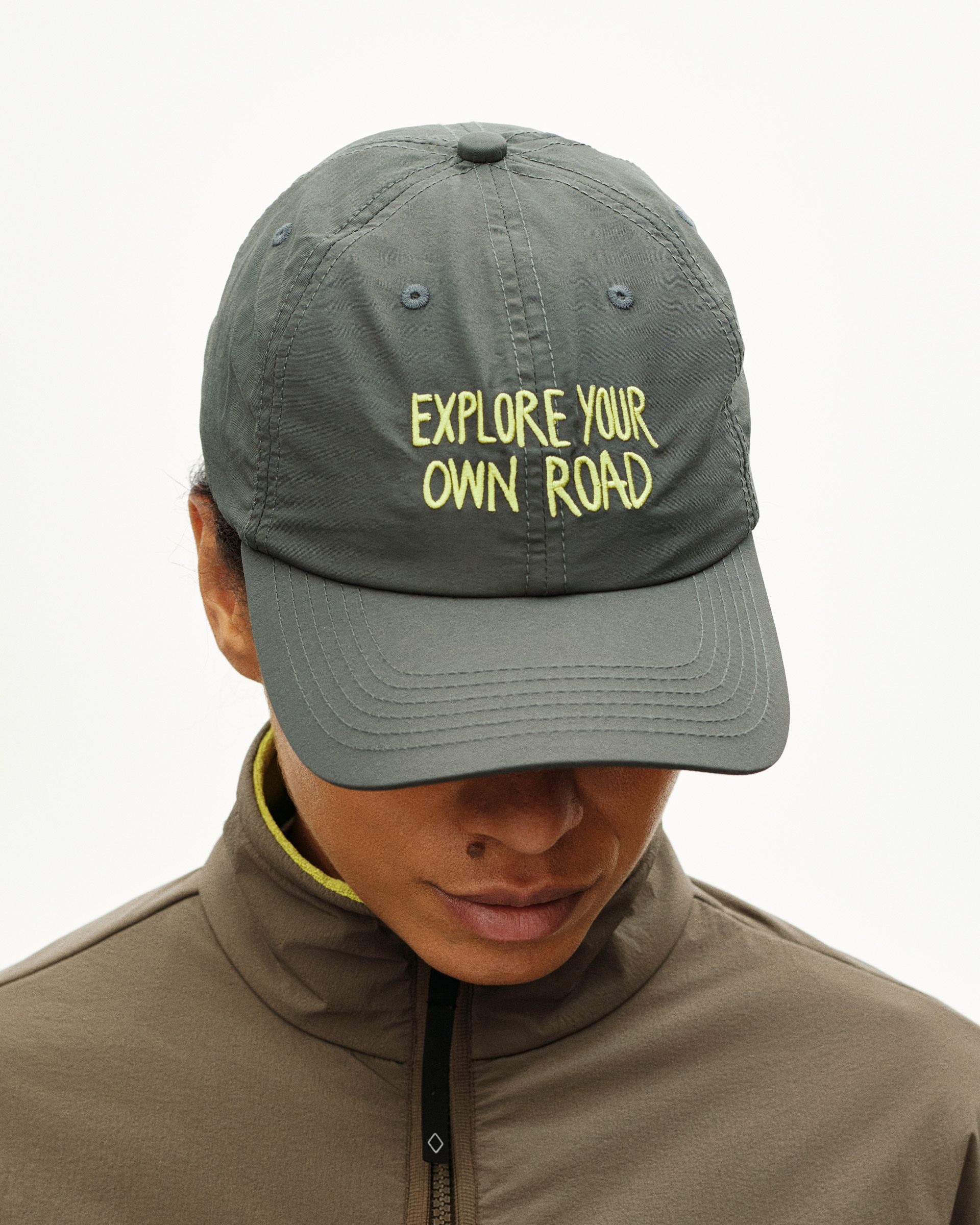 Grey Off-Race cap on model with yellow Explore Your Own Road embroidered text