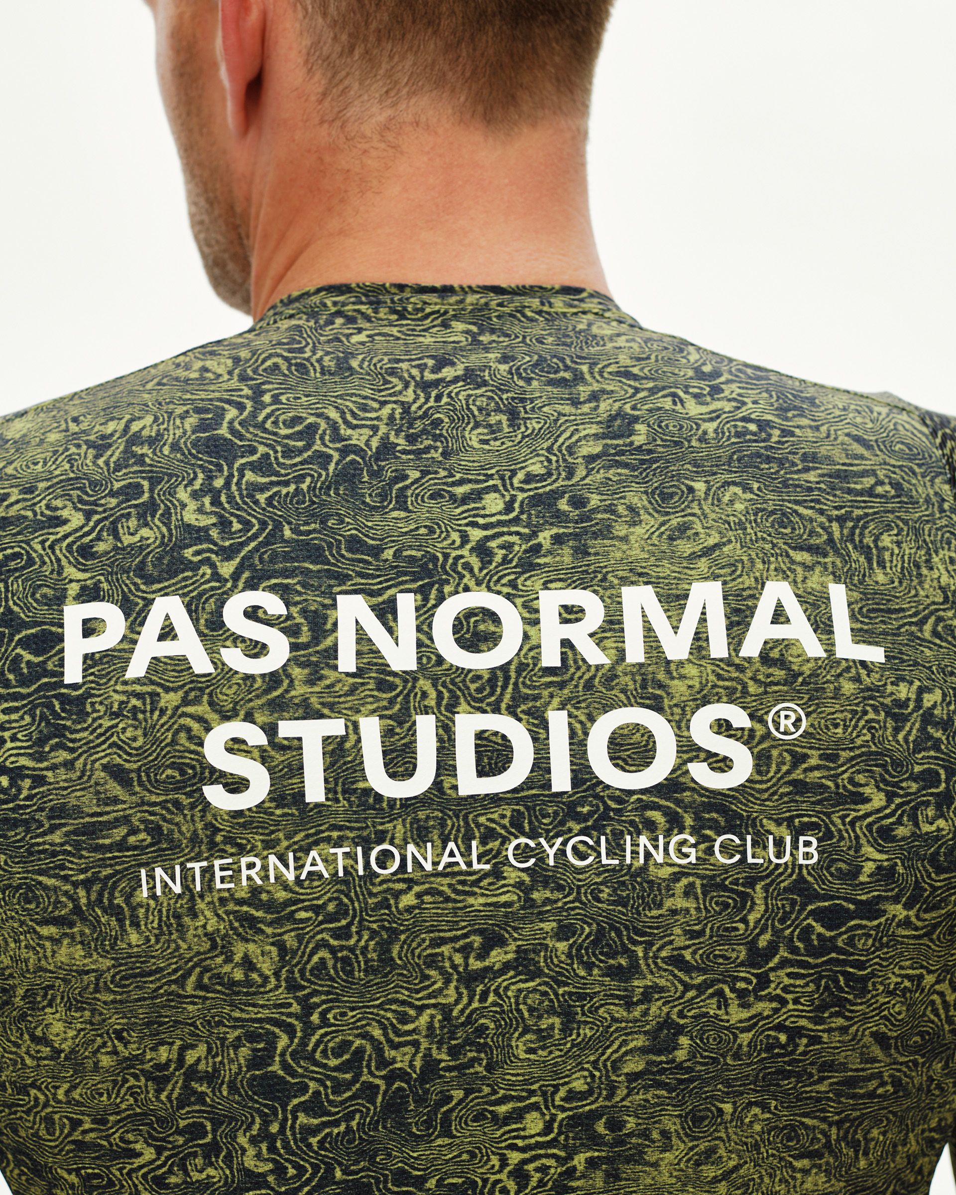 Dark Lime Essential cycling jersey, rear detail on model with topographic AOP and white back logo print