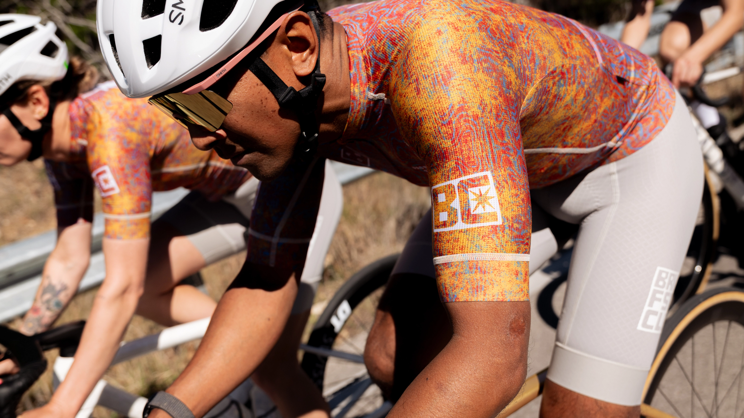 Orange Mechanism Breakfast Club bibs on cyclist in racing position with multicolor abstract print