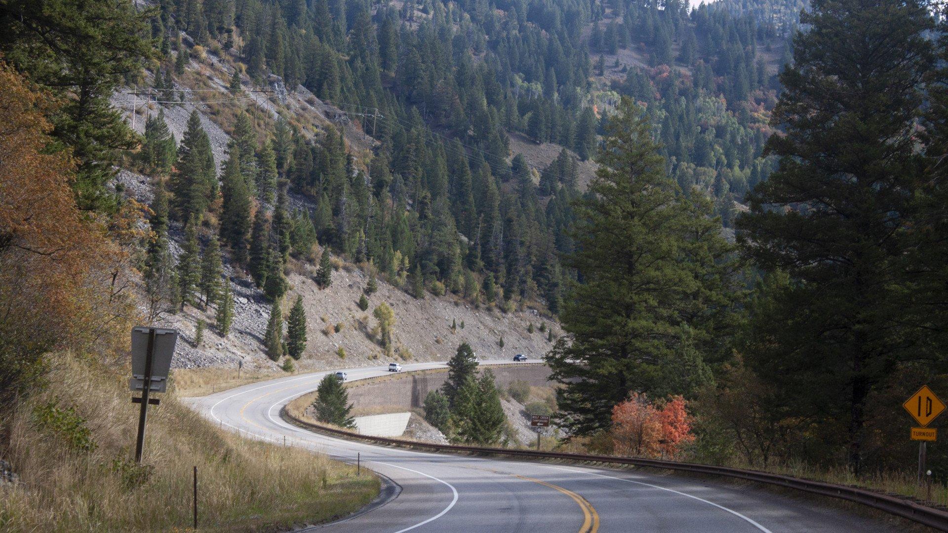 Winding mountain road through forested valley with autumn colors and steep hillsides