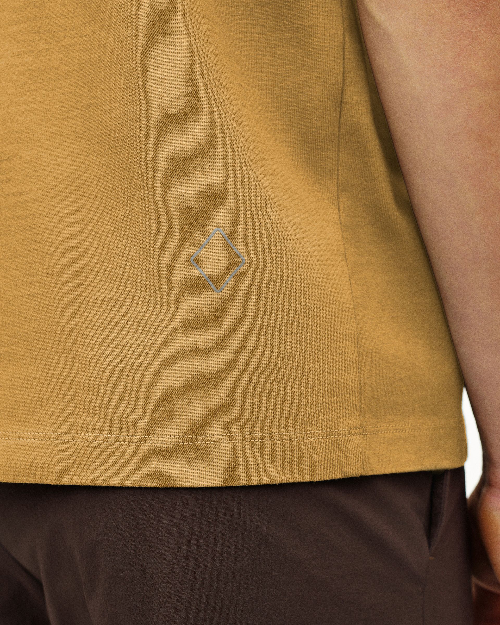 Sandstone Off-Race T-shirt, detail view on model showing tonal diamond logo at hem