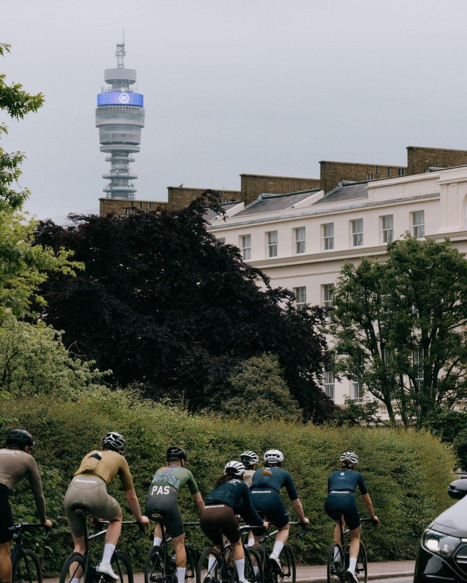 Group of cyclists in cycling apparel riding through London park with BT Tower in background