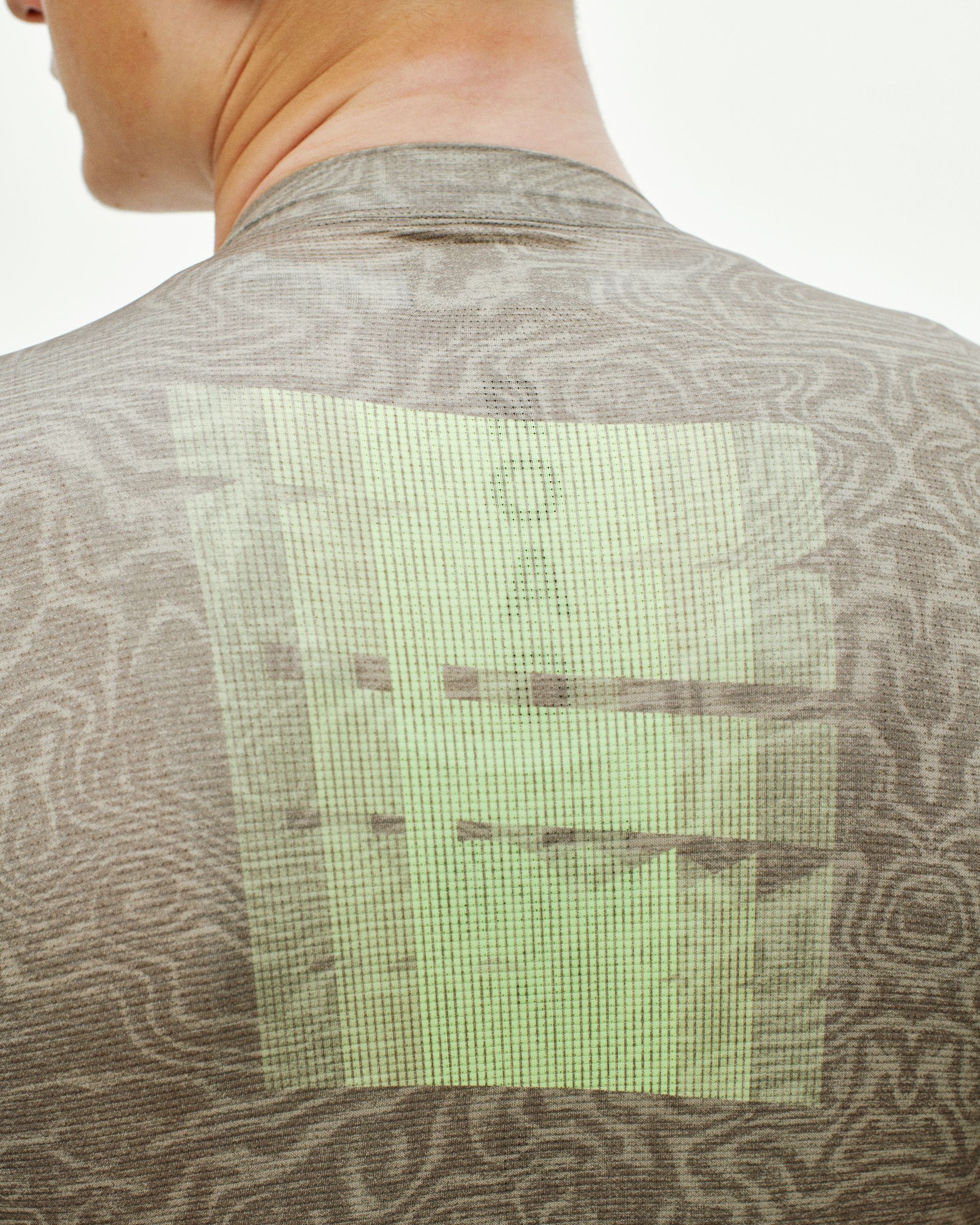 Brown Mechanism cycling jersey, rear detail on model with green logo graphic on topo print fabric