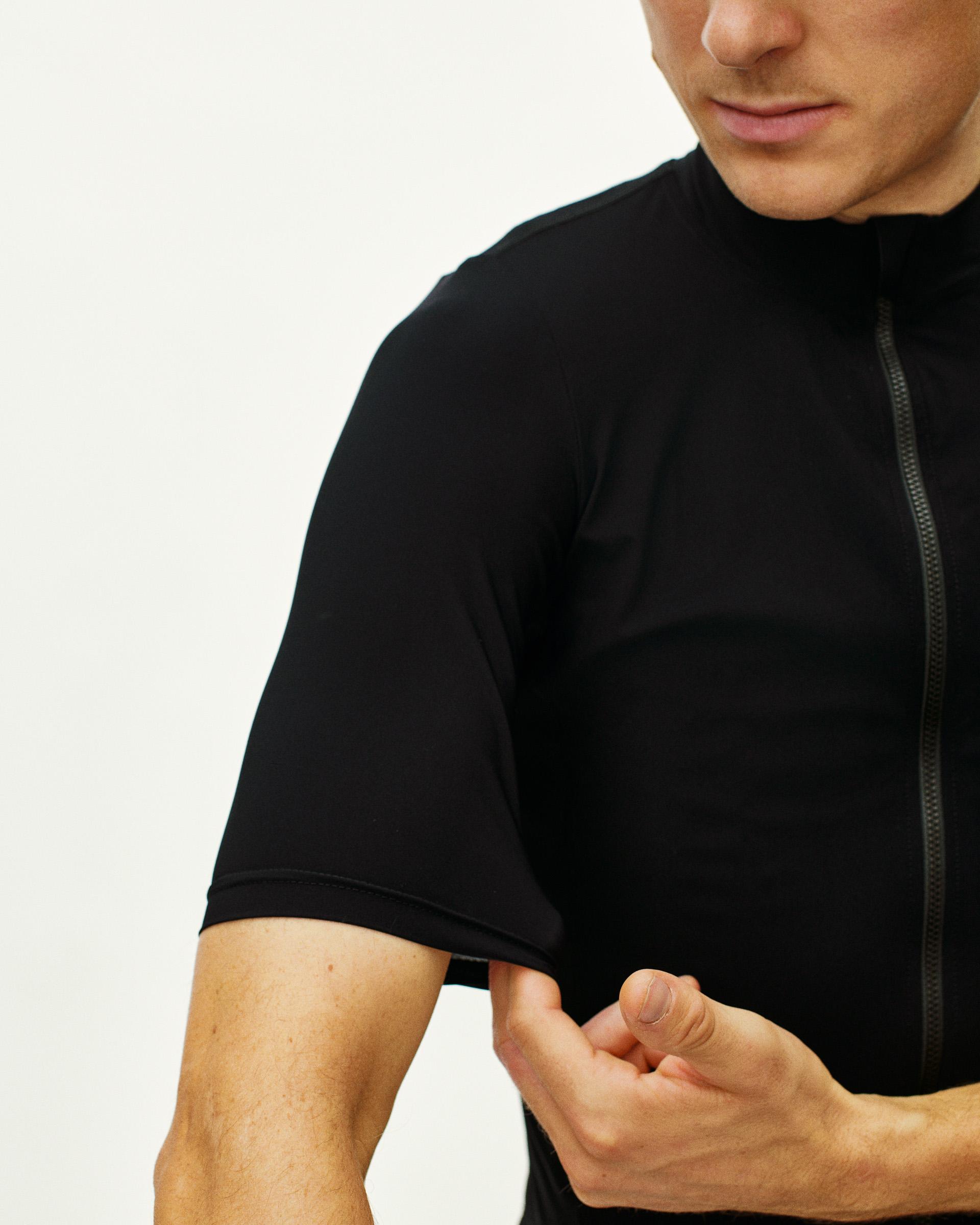 Black Essential cycling jersey on model, front three-quarter view with contrast zip