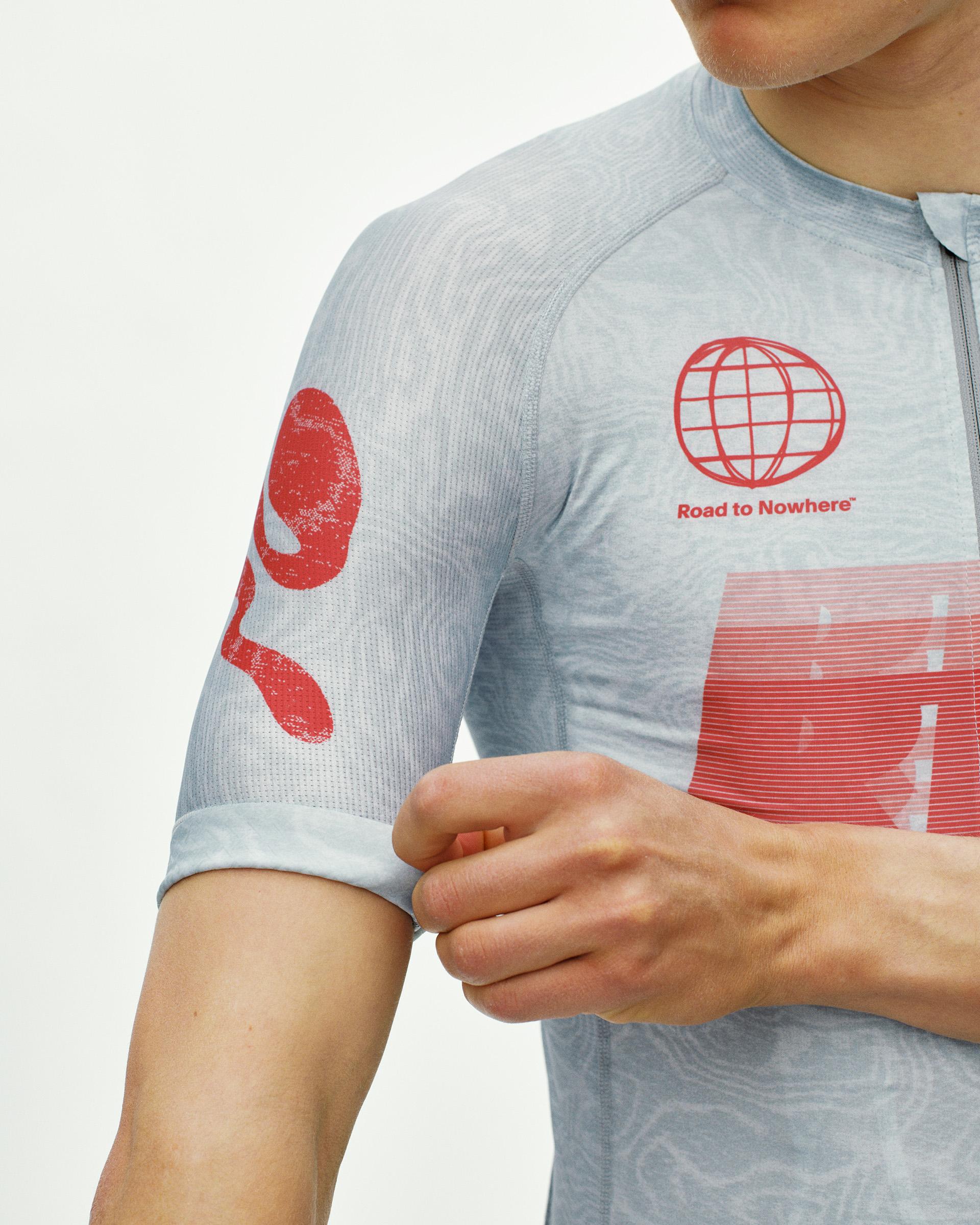 Light Blue Mechanism cycling jersey on model, detail view with red Road to Nowhere globe chest print and sleeve graphic