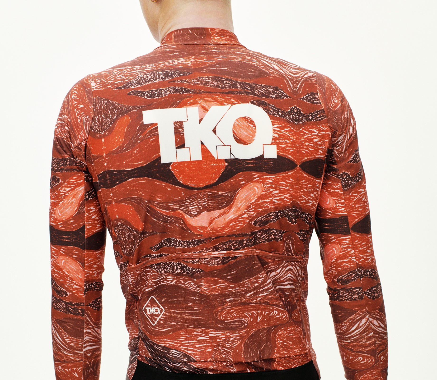 Red T.K.O. Woven long sleeve cycling jersey, rear view on model with white T.K.O. logo and abstract print