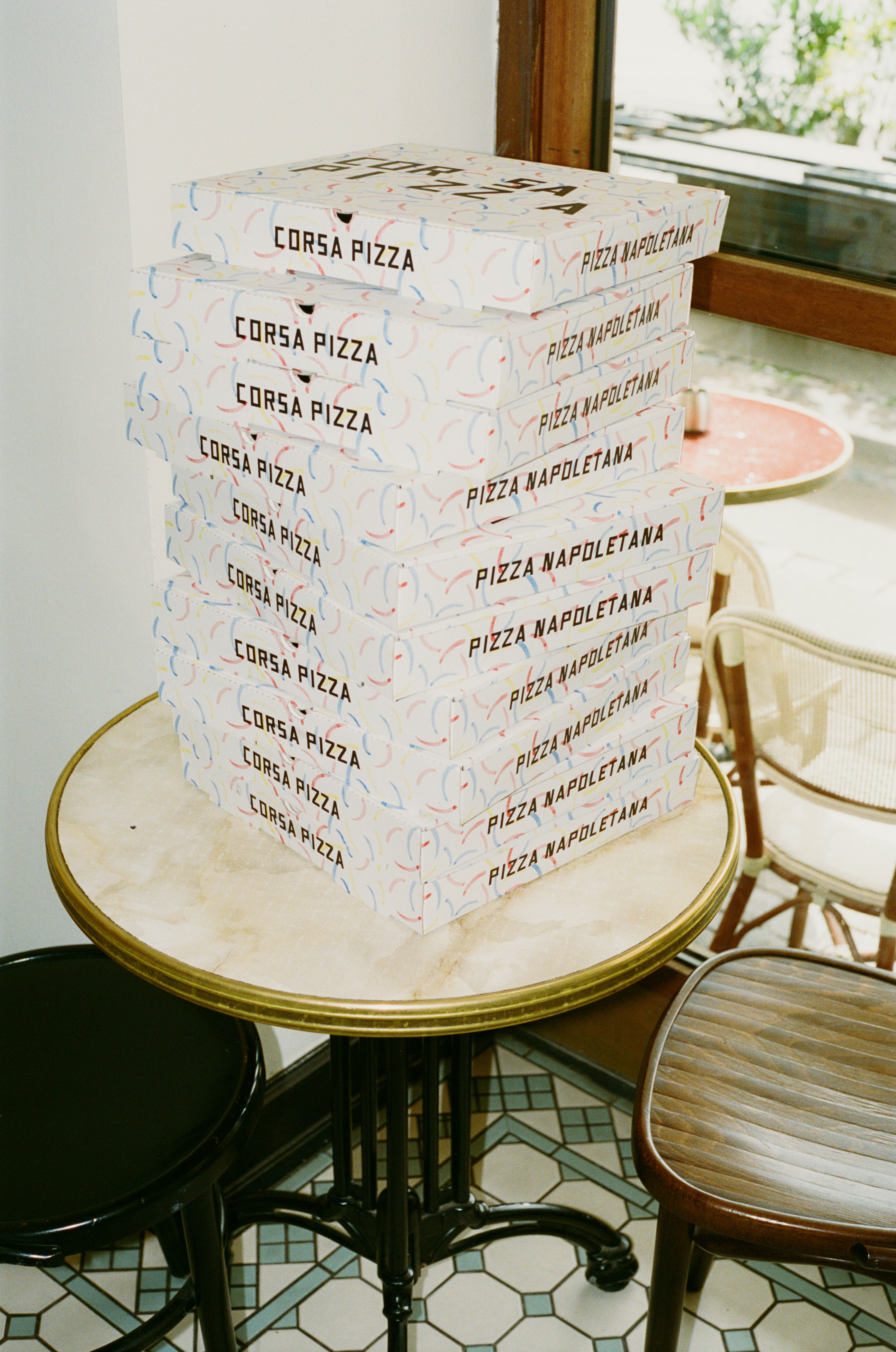 Stack of pizza boxes on cafe table with geometric tiled floor
