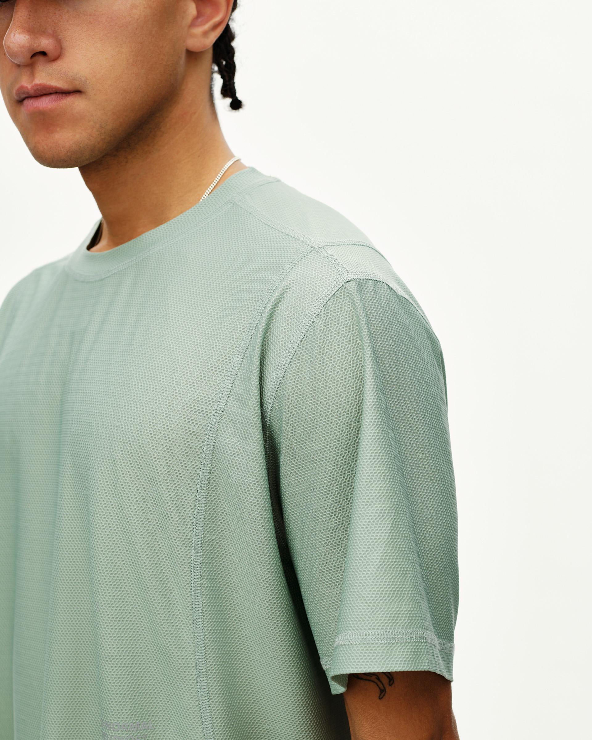 Green Sage Balance T-shirt on model, front detail view with textured mesh fabric and curved seams