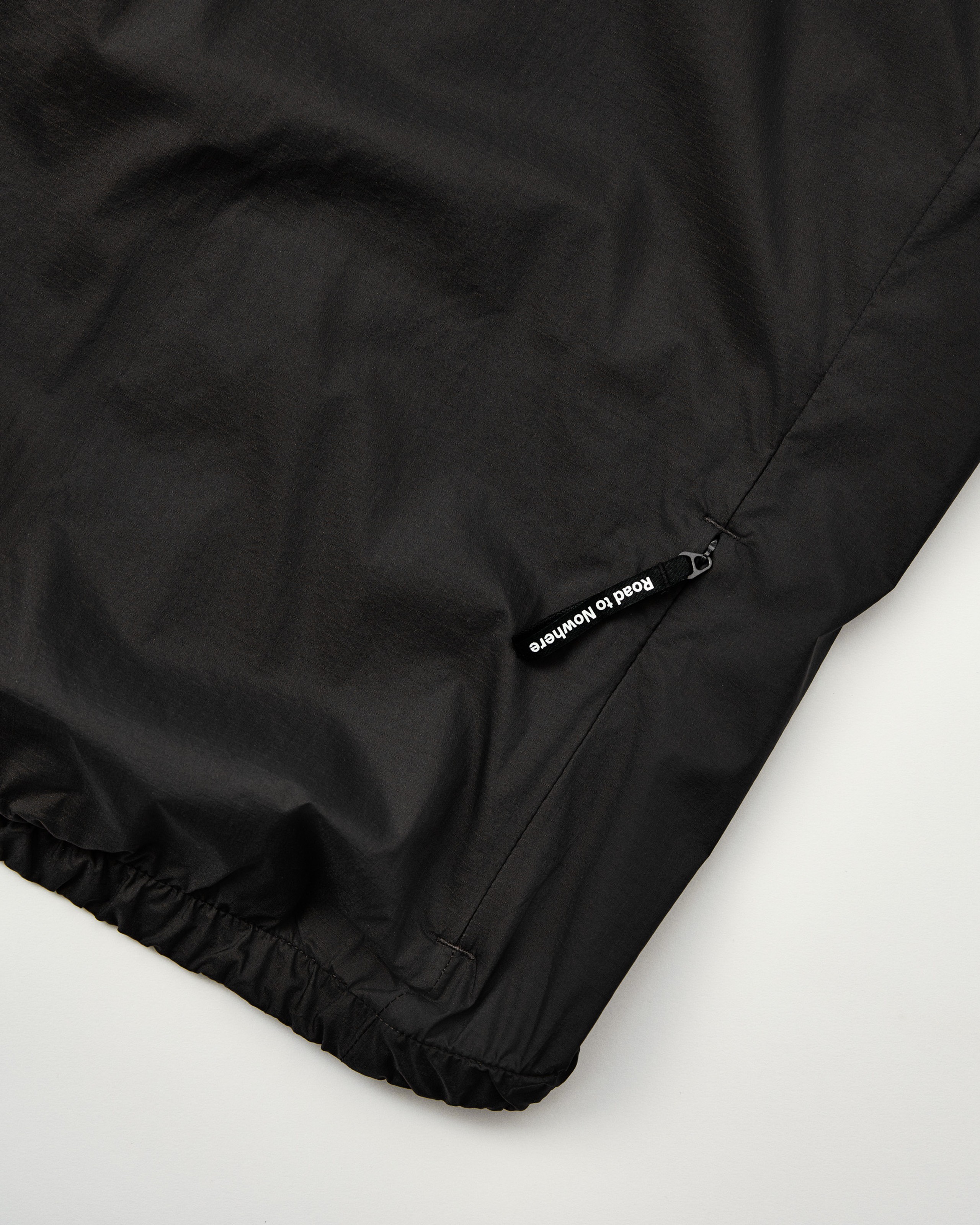 Navy Essential Insulated jacket detail showing elastic hem with white Road to Nowhere brand label