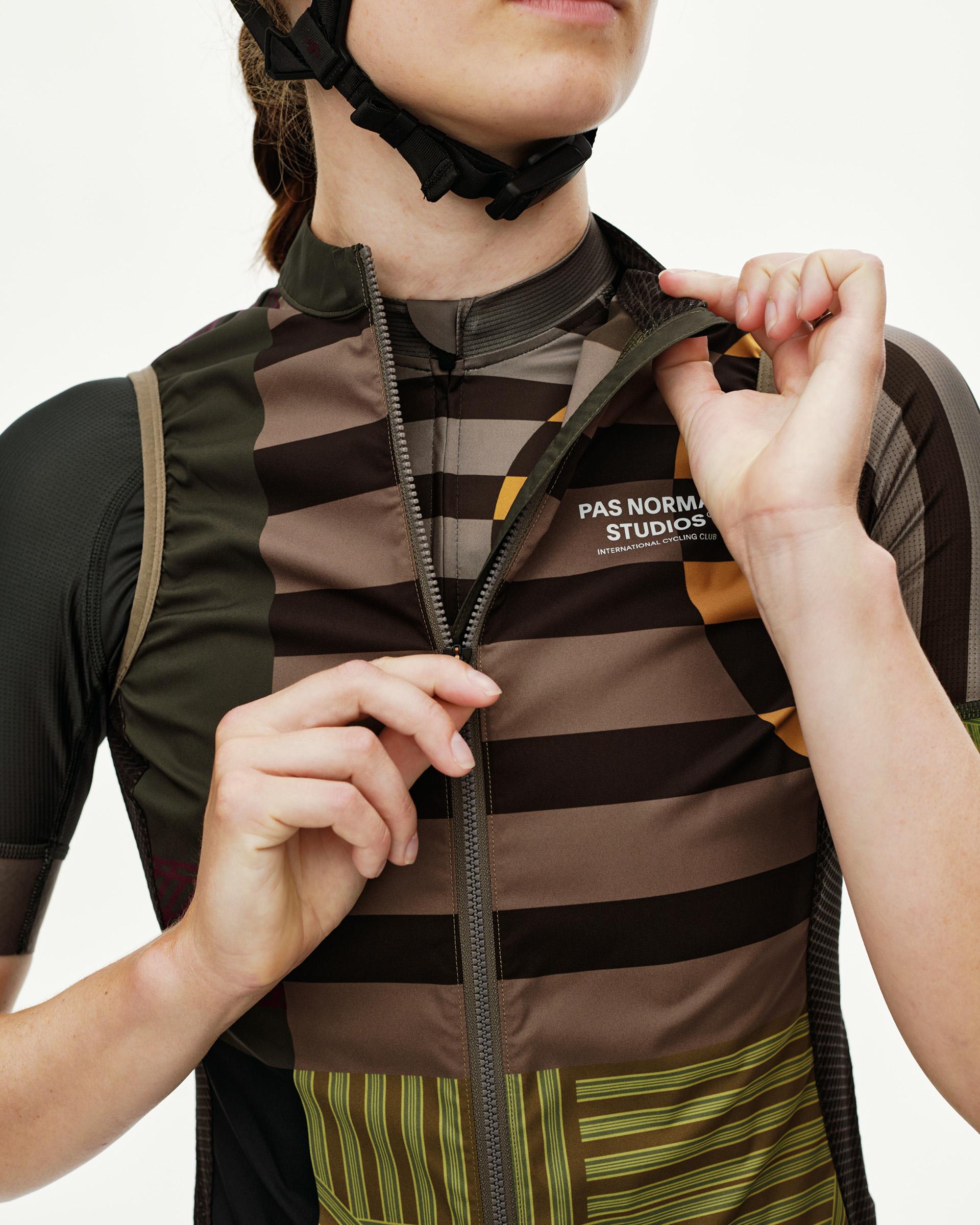 Dusty Earth khaki Mechanism Stow Away cycling gilet, front detail on model with full-zip and stripe print