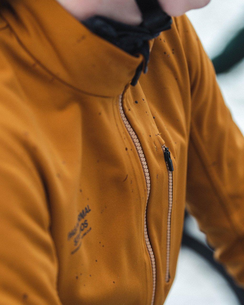 Orange jacket detail showing zip closure and chest branding with water droplets