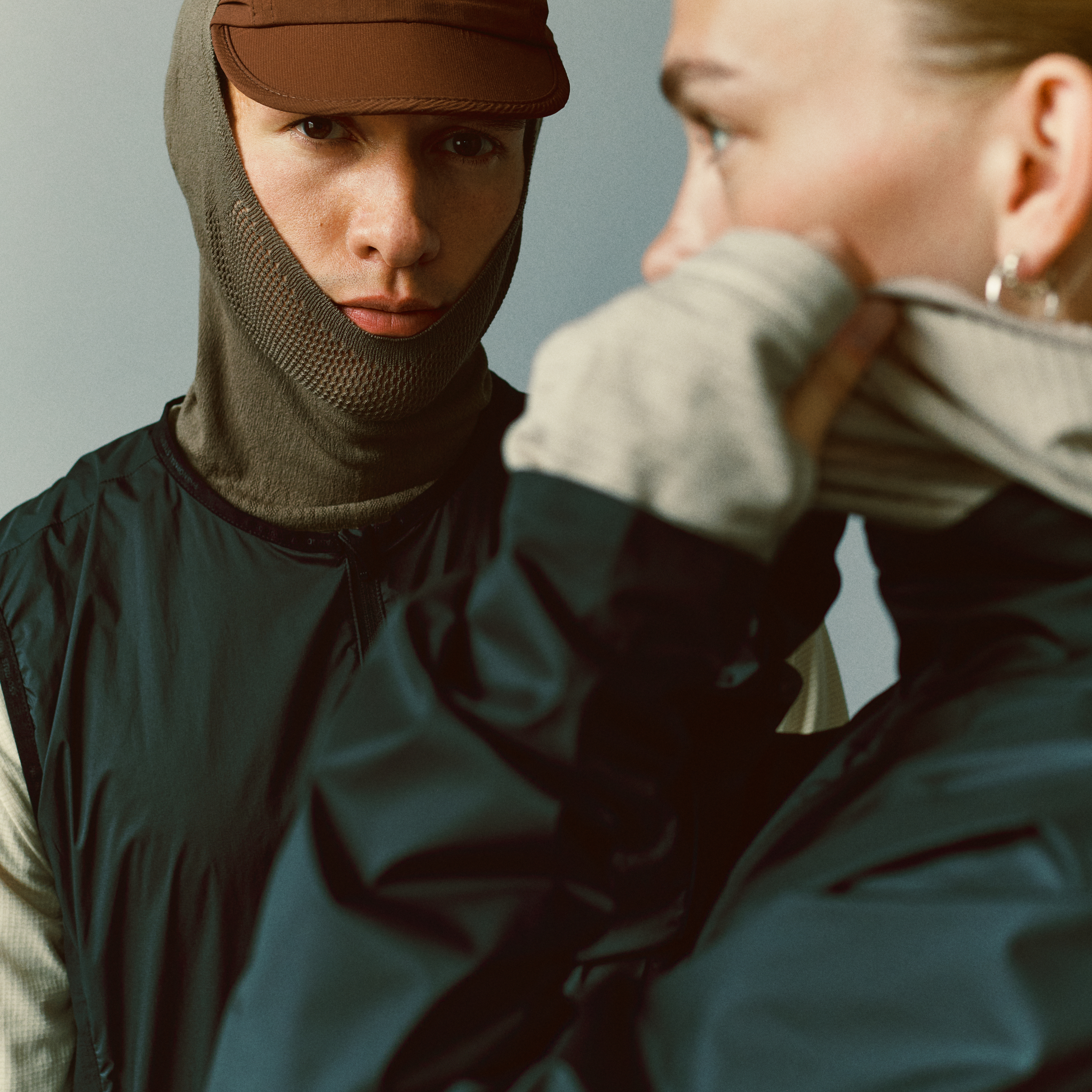 Dark teal Balance cycling windproof vest on model, front view worn over base layer with balaclava