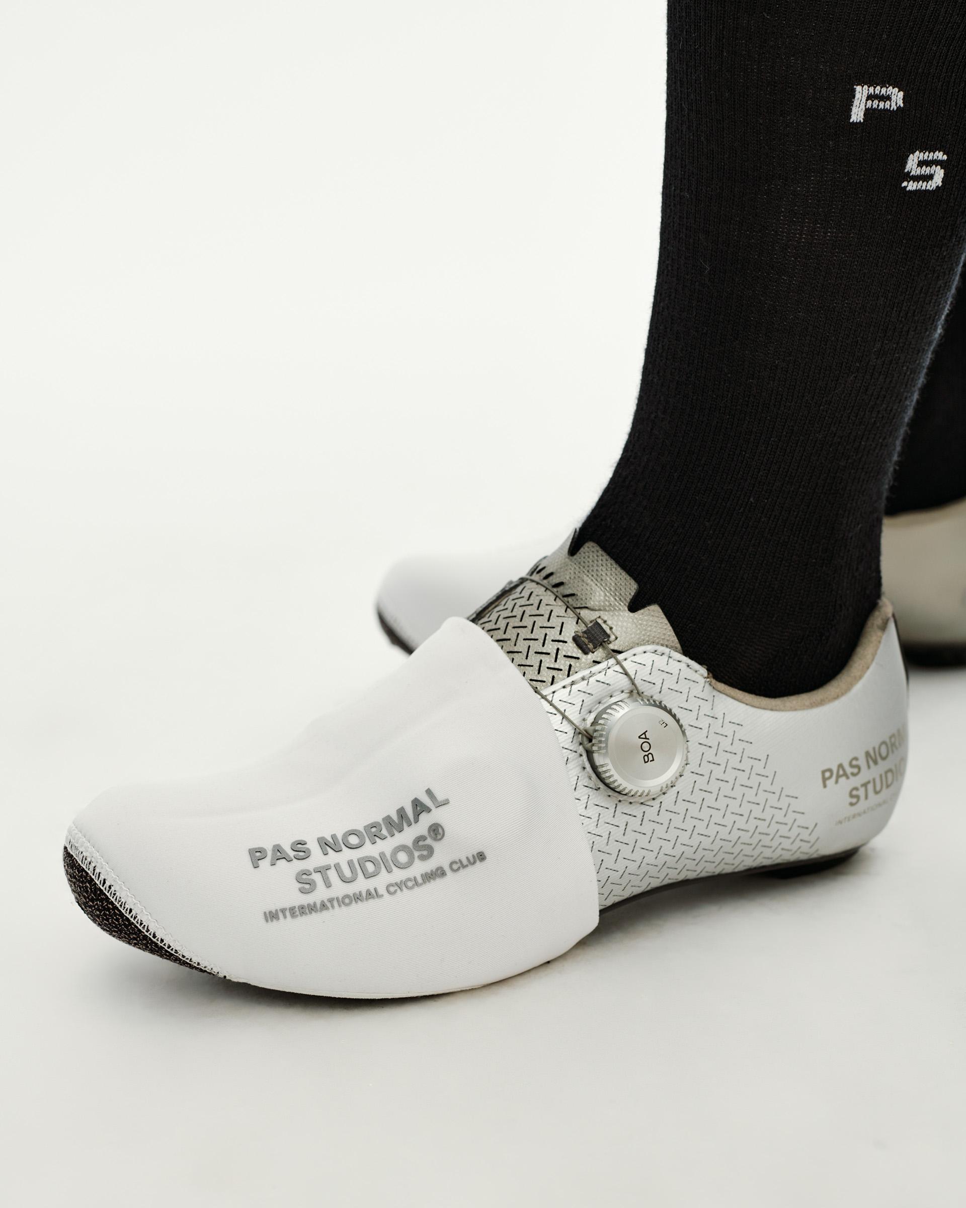 White Logo Toe Cover cycling overshoe on model, side view with branded text print