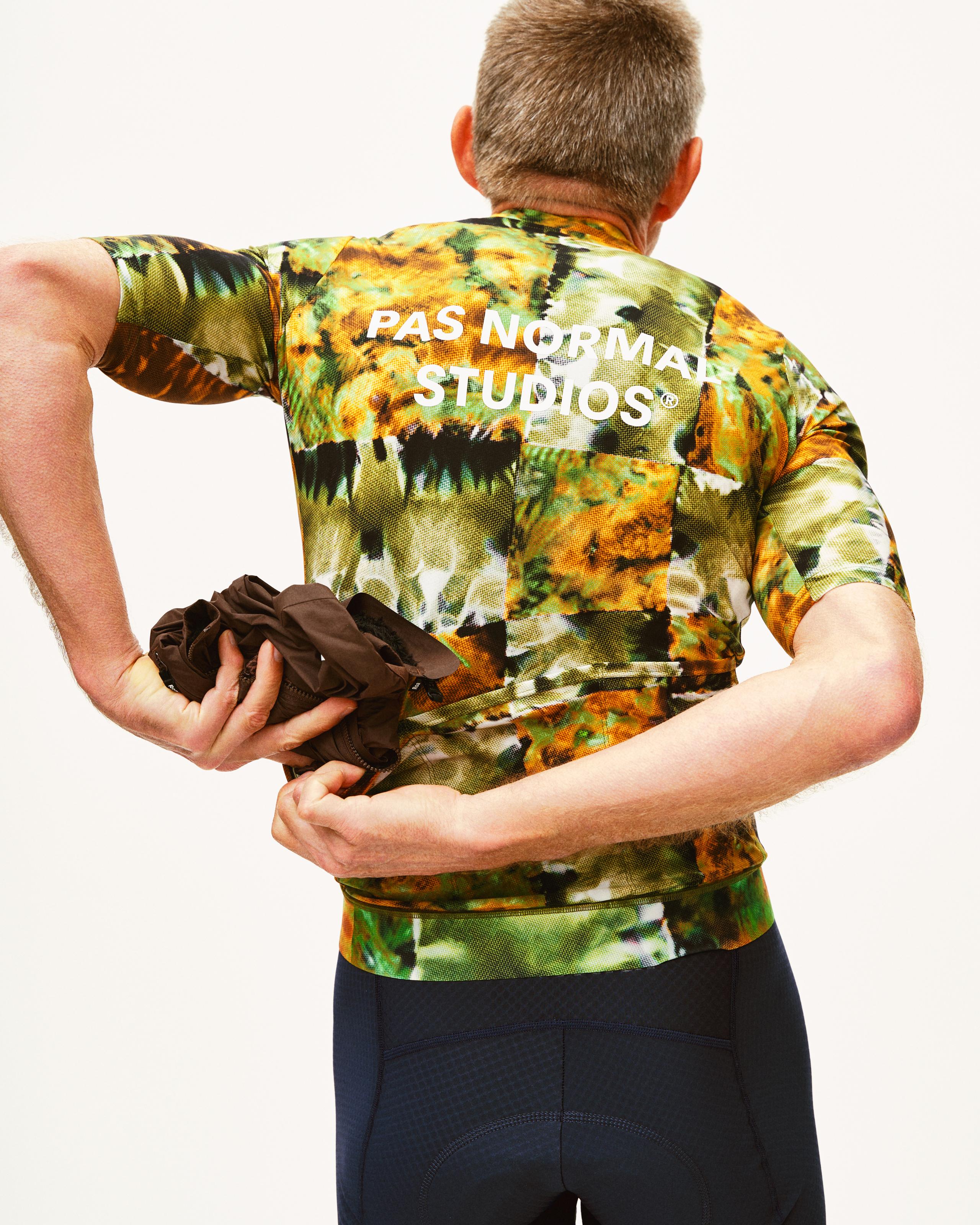 Green Essential cycling jersey on model, rear view with kaleidoscope print and white back logo