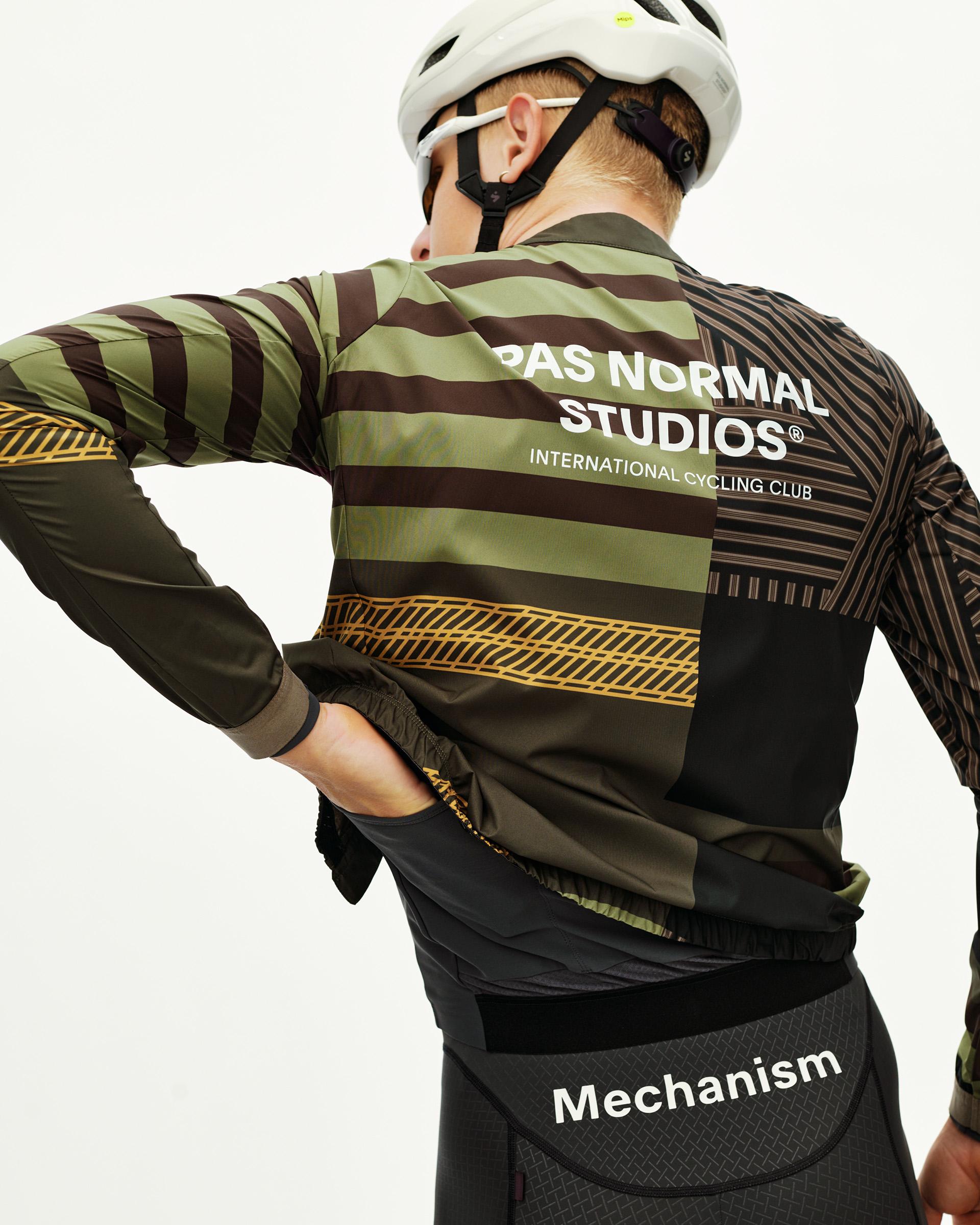 International Green Mechanism Stow Away cycling jacket on model, rear view with stripe and gold graphic print
