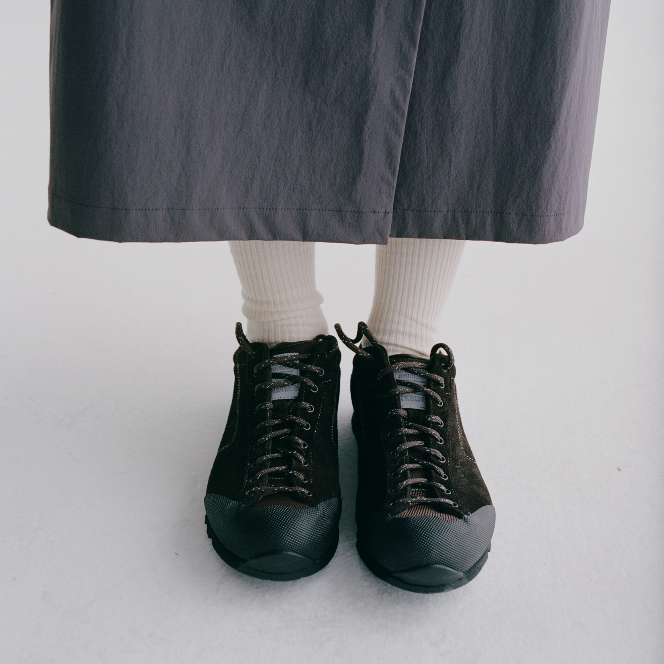 Black lace-up cycling shoes with textured toe cap worn with cream ribbed socks and grey trousers