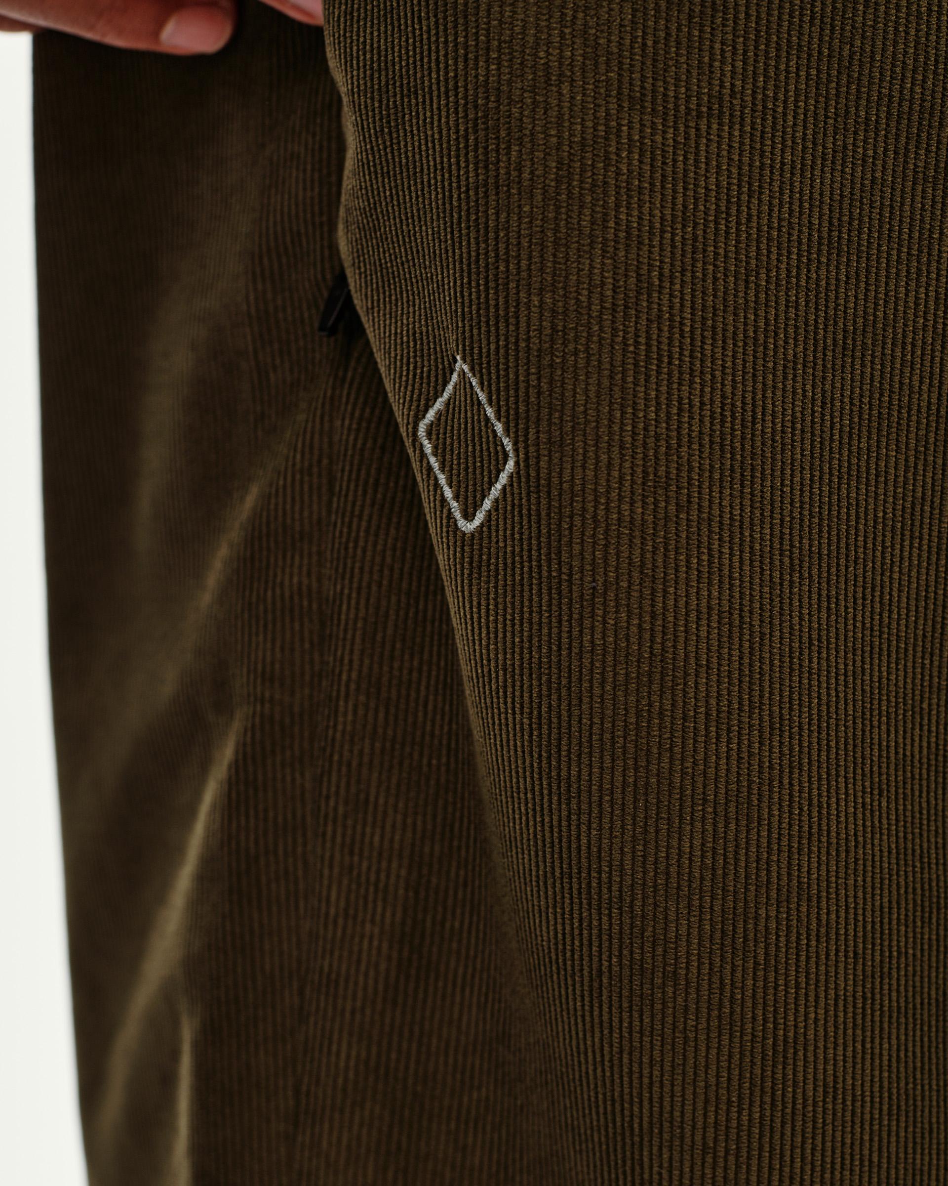 Deep Olive Off-Race Corduroy pants, detail view showing embroidered diamond logo on corduroy fabric