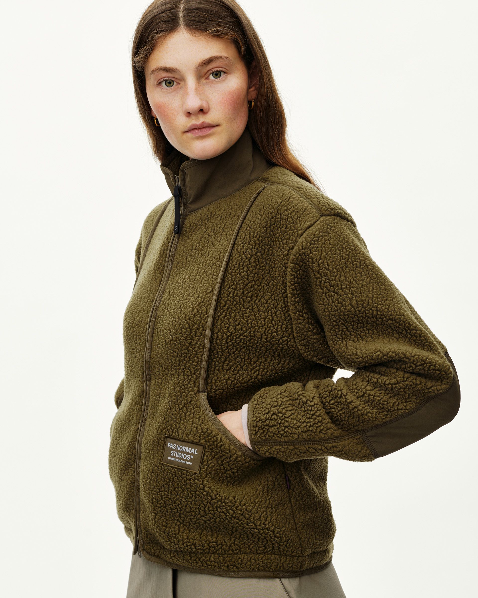 Deep Olive Off-Race Pile Fleece jacket on model, three-quarter front view with full zip and woven label patch