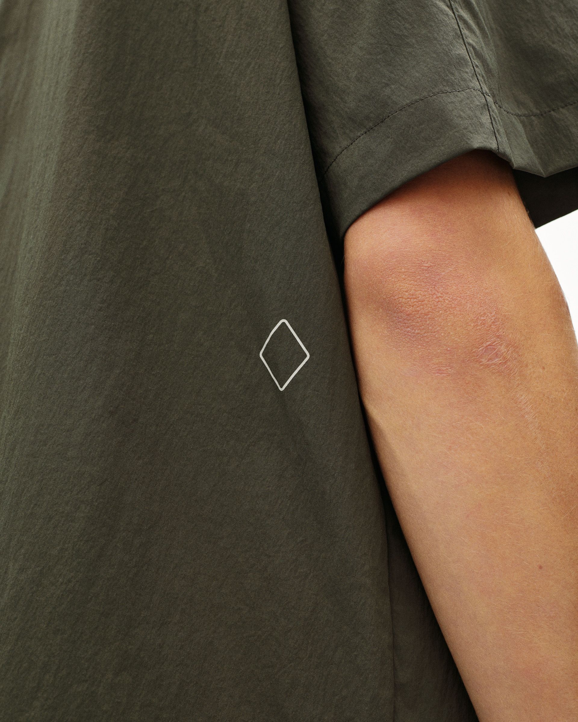 Dark Grey Off-Race Light Tech Shirt detail view on model with white diamond logo