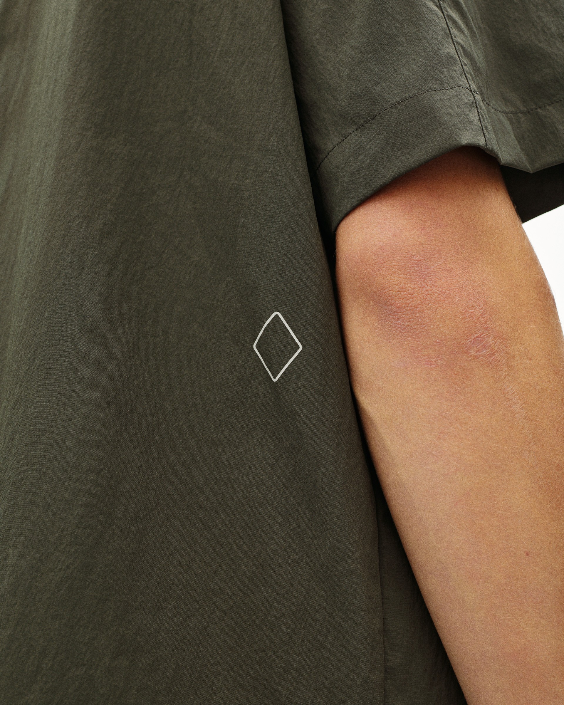 Dark Grey Off-Race Light Tech Shirt detail view on model with white diamond logo