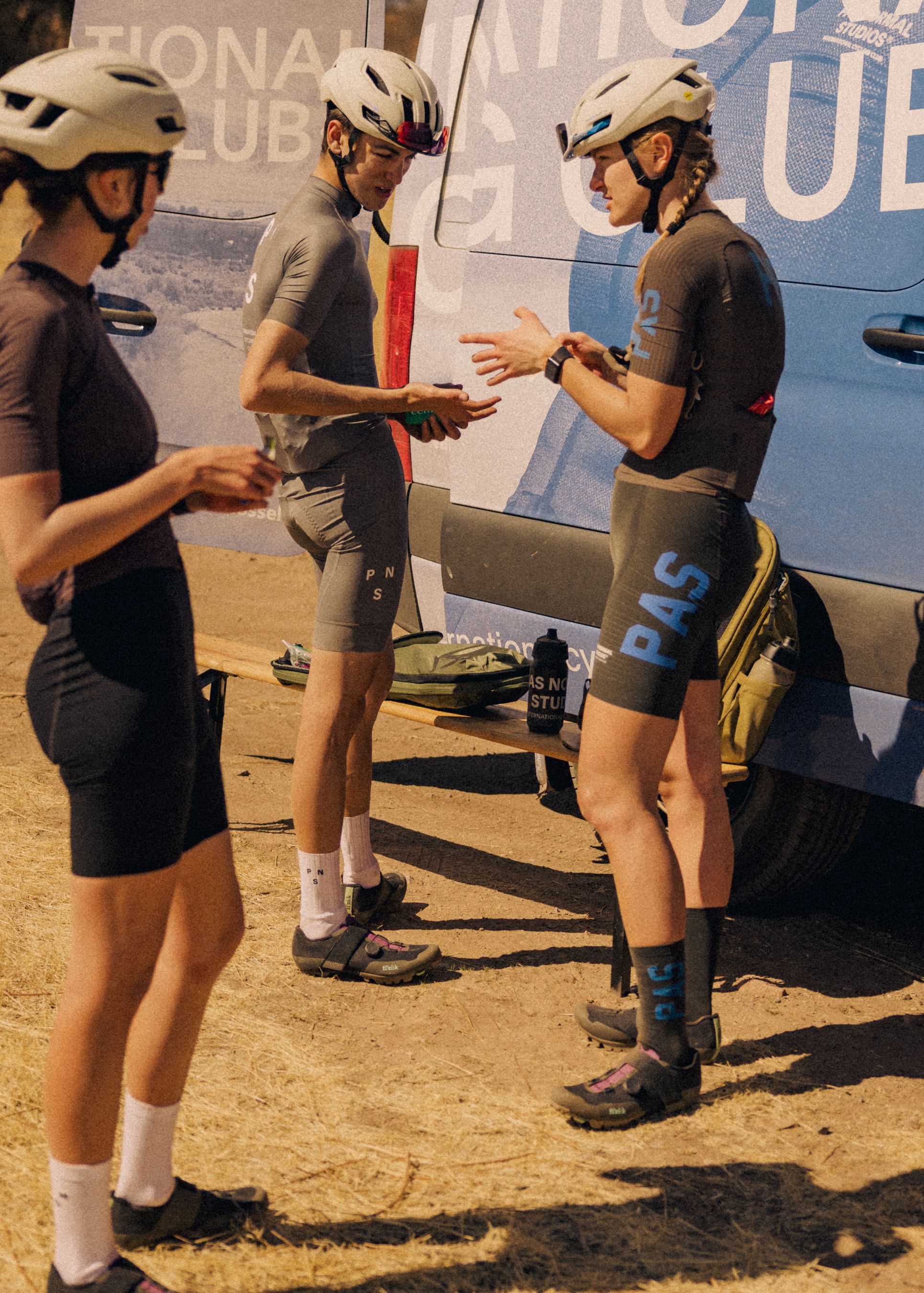 Models wearing grey cycling kits with helmets and sunglasses at desert training camp