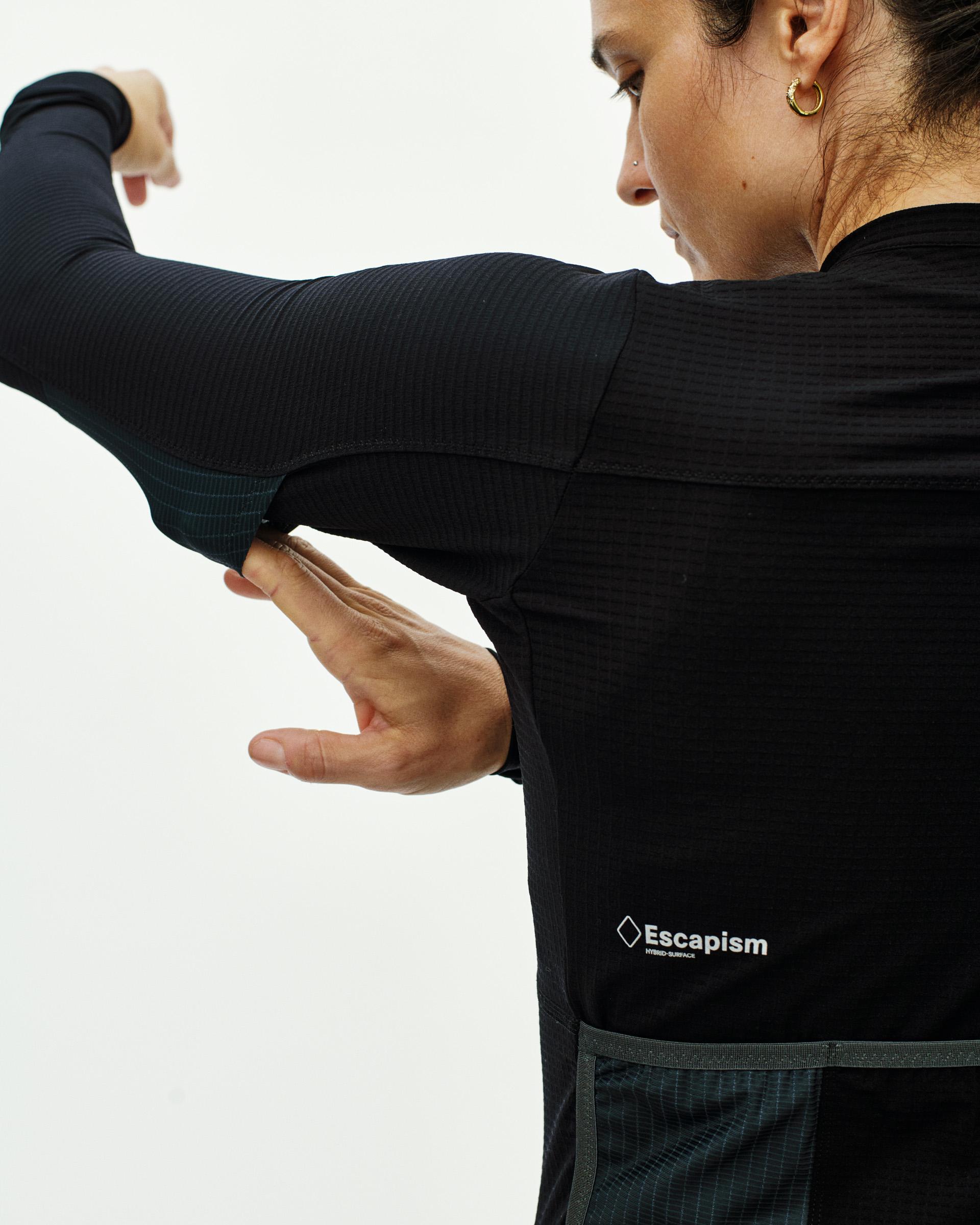 Black Escapism long sleeve cycling jersey on model, side view with white chest logo