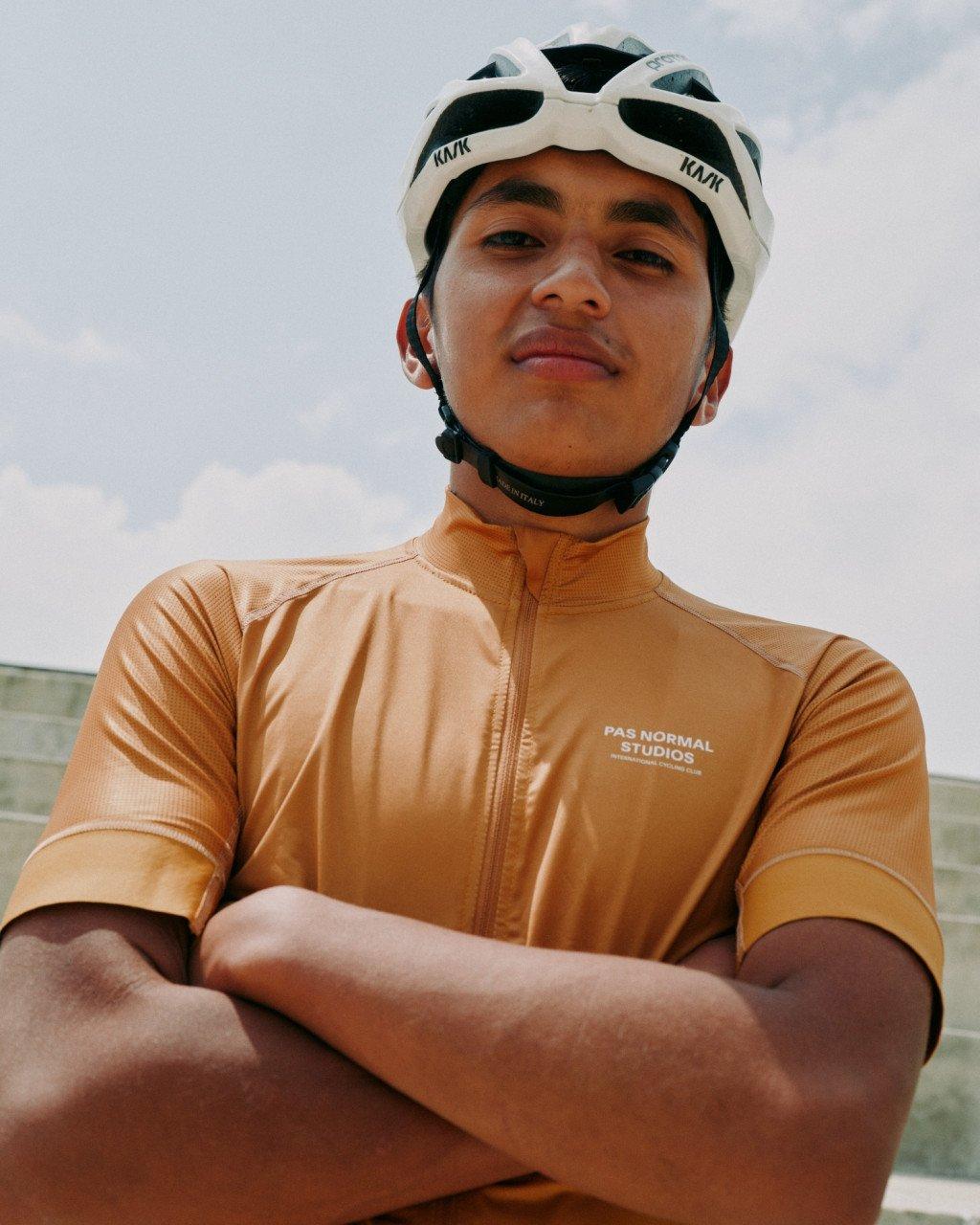 Model wearing orange cycling jersey with logo and white cycling helmet