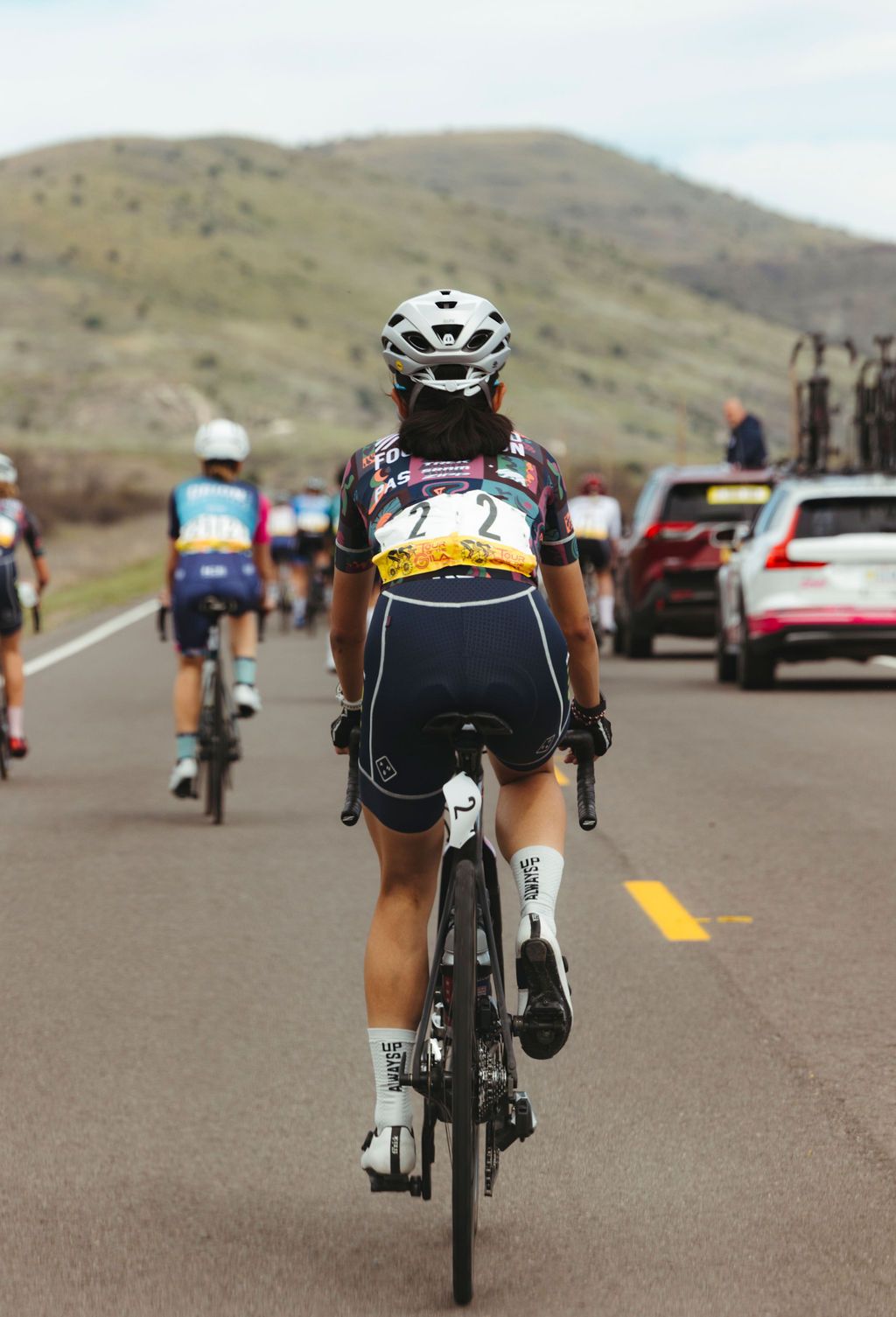 Cyclist in colorful jersey and dark shorts riding on desert road during race
