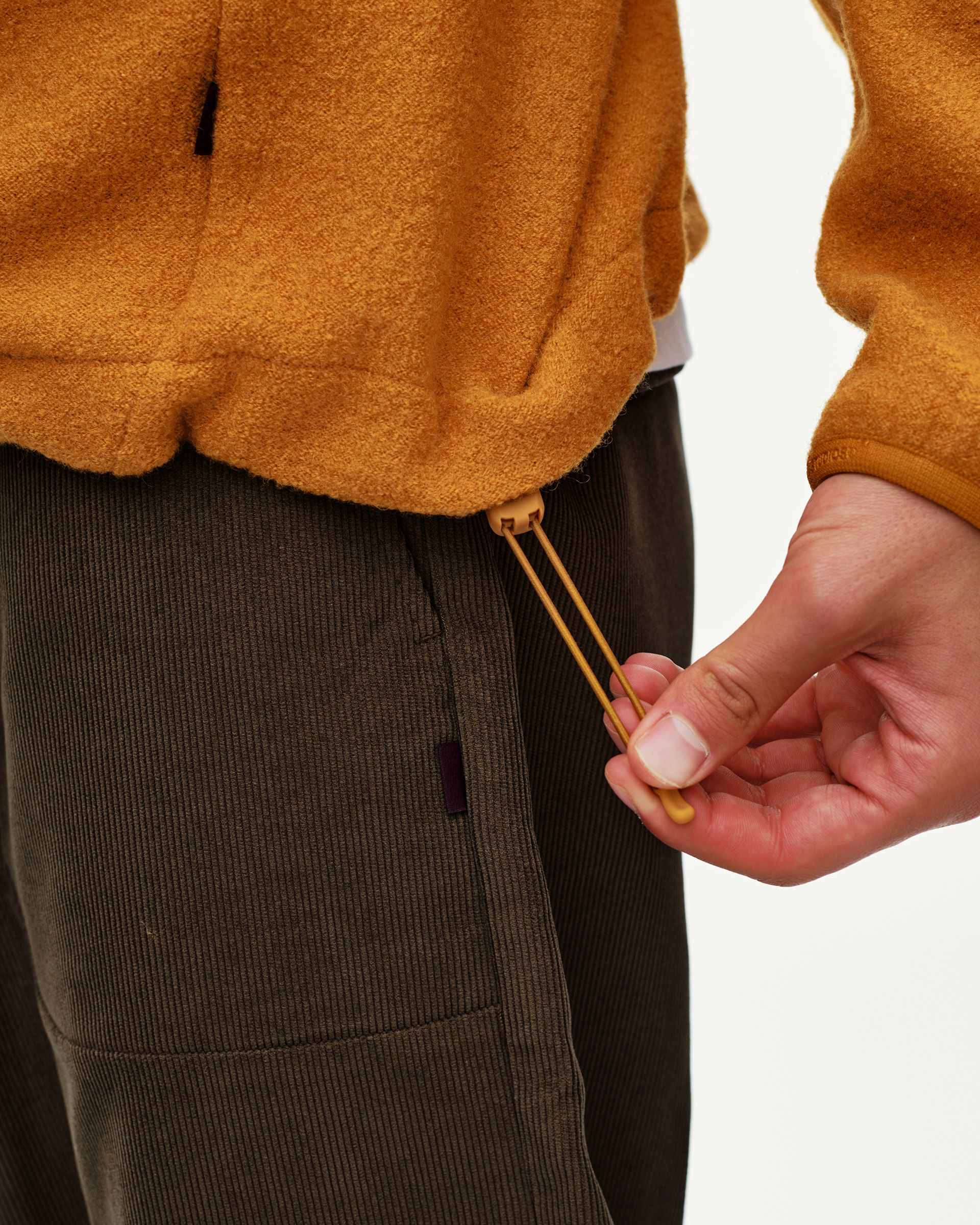 Ochre Off-Race Boiled Wool Half-Zip outerwear, detail view of drawcord hem toggle on model