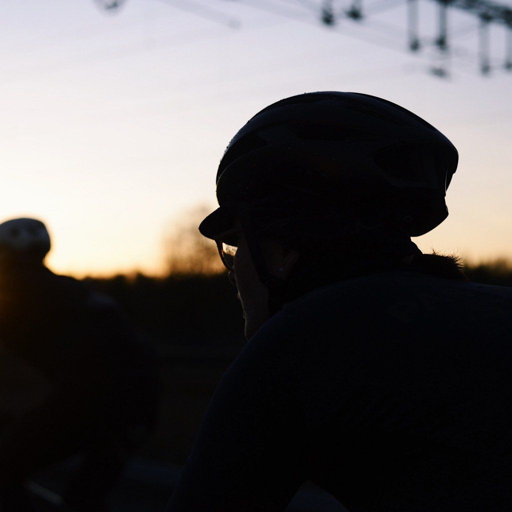Model wearing cycling cap silhouetted against sunset sky