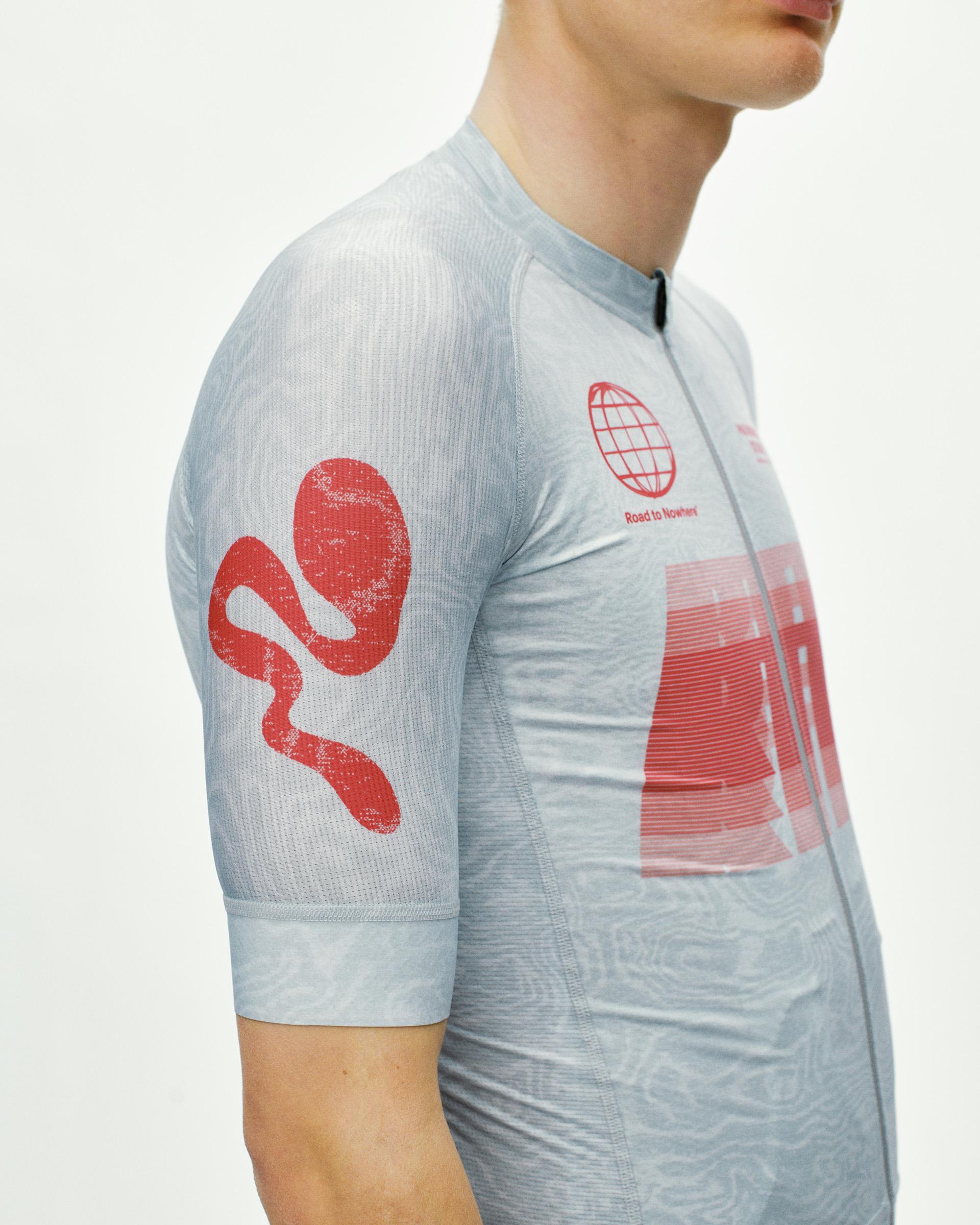 Light Aqua Mechanism cycling jersey on model, side view with red graphic print on chest and sleeve
