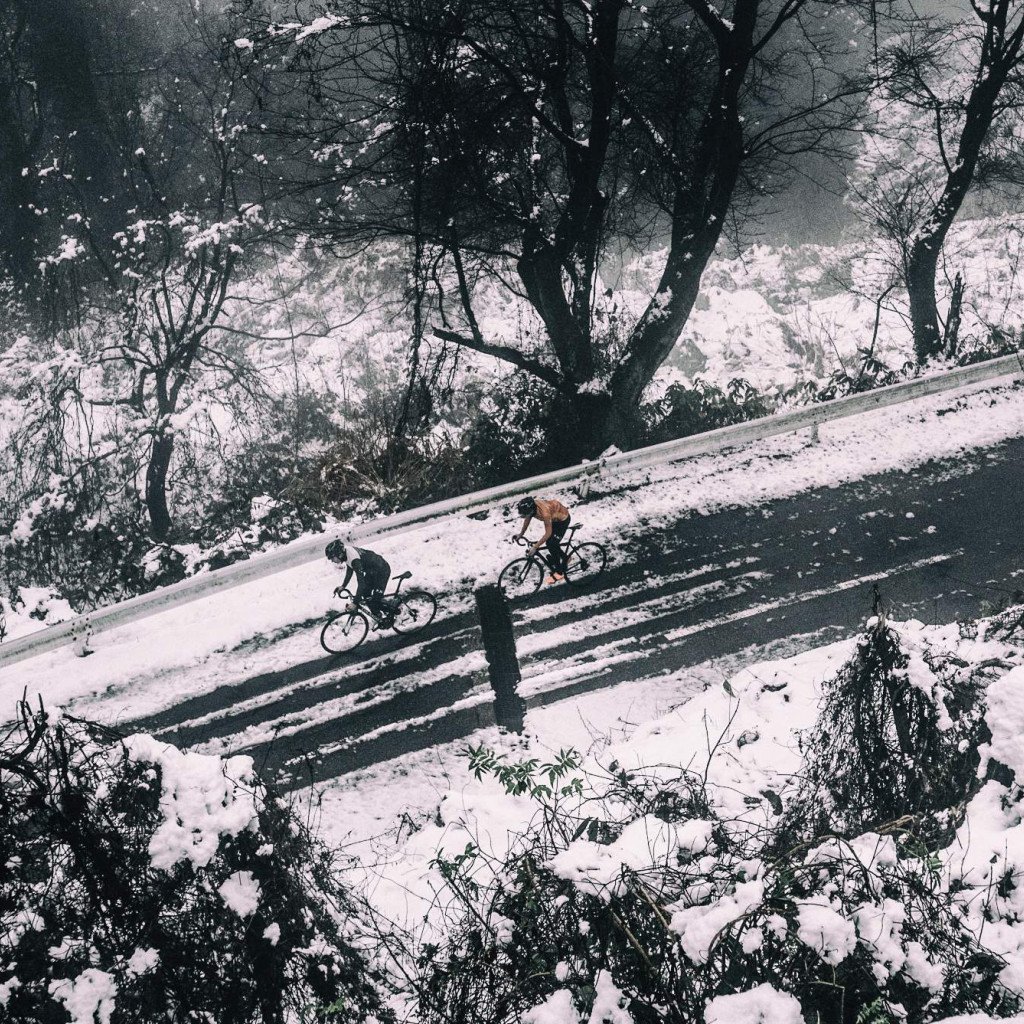 Two cyclists riding on snowy road through winter landscape in Toyama, Japan